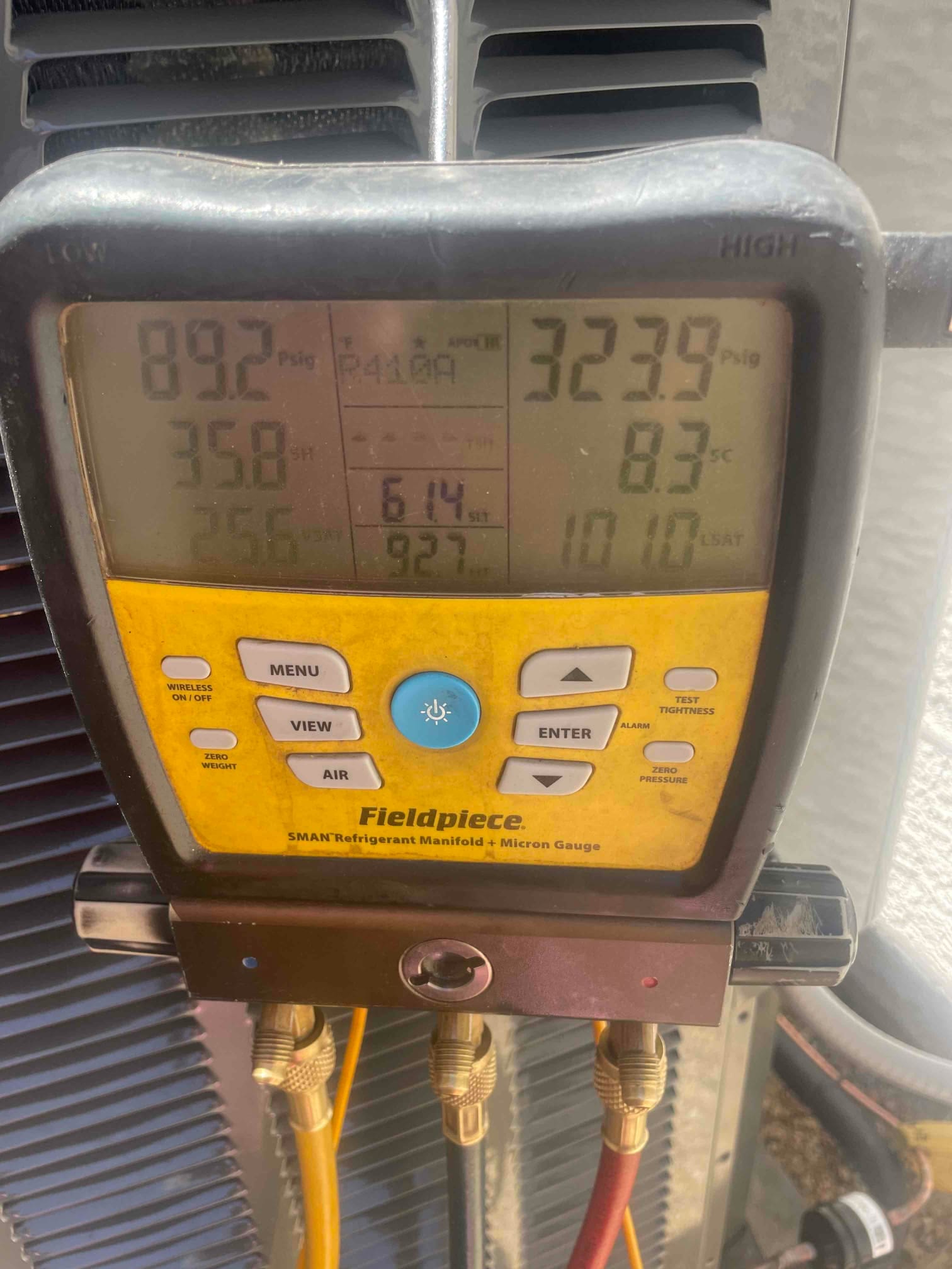 Digital manifold on the outdoor unit shows operating pressures with superheat and subcooling during system commissioning.