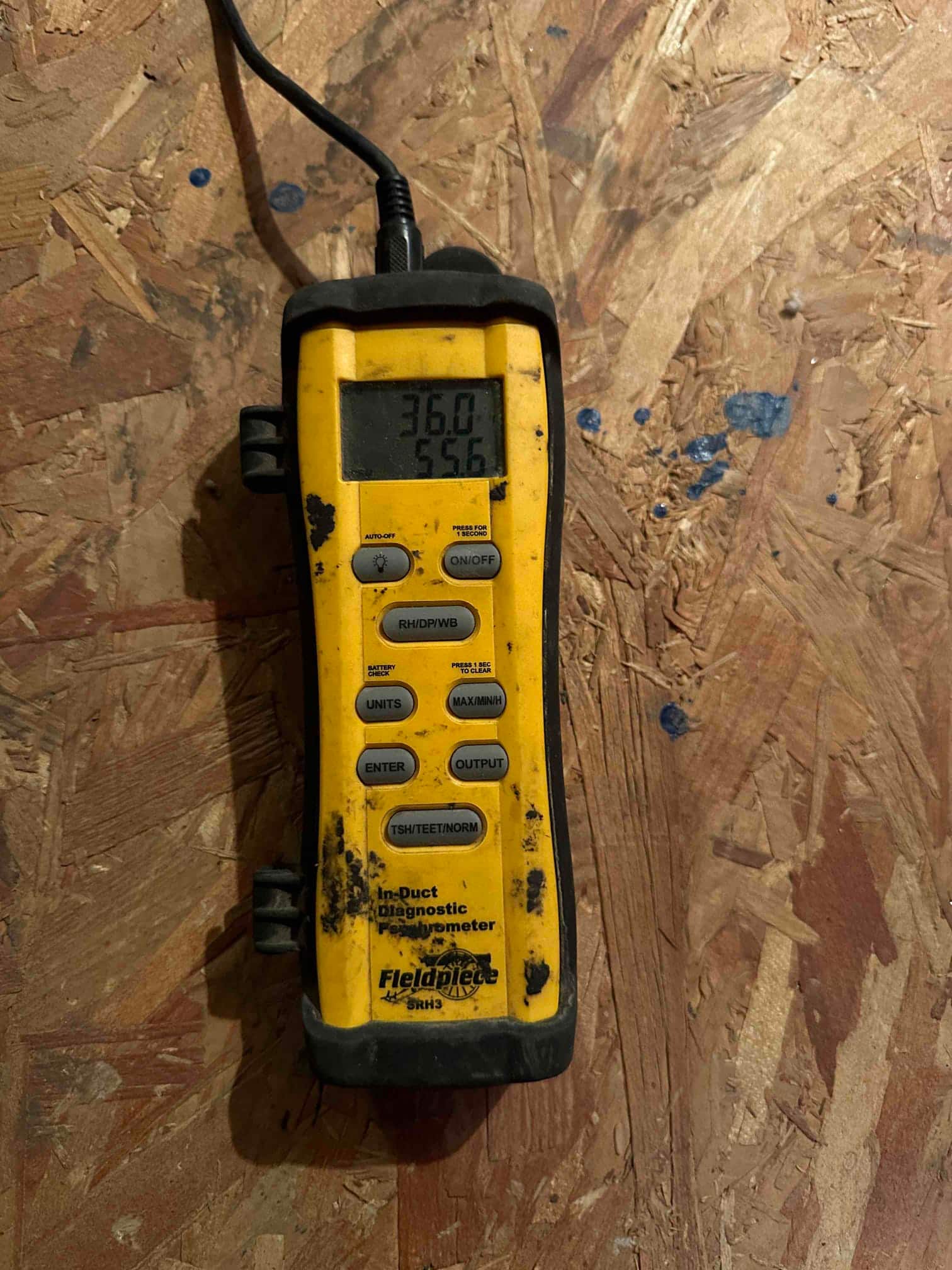 Digital meter displays 55.6 degrees Fahrenheit, documenting supply air temperature measurement during commissioning.