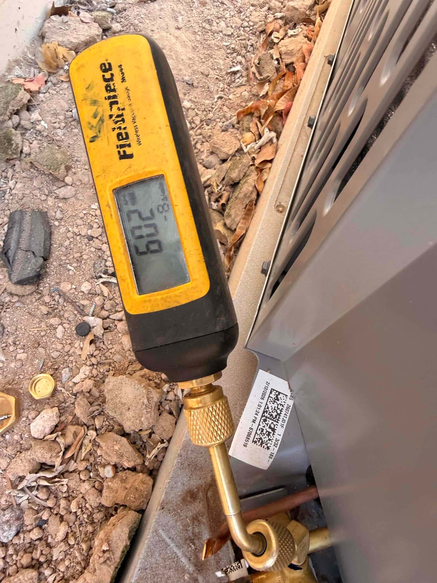 Digital micron gauge connected at the service port reads 602 microns during system evacuation before refrigerant charging.