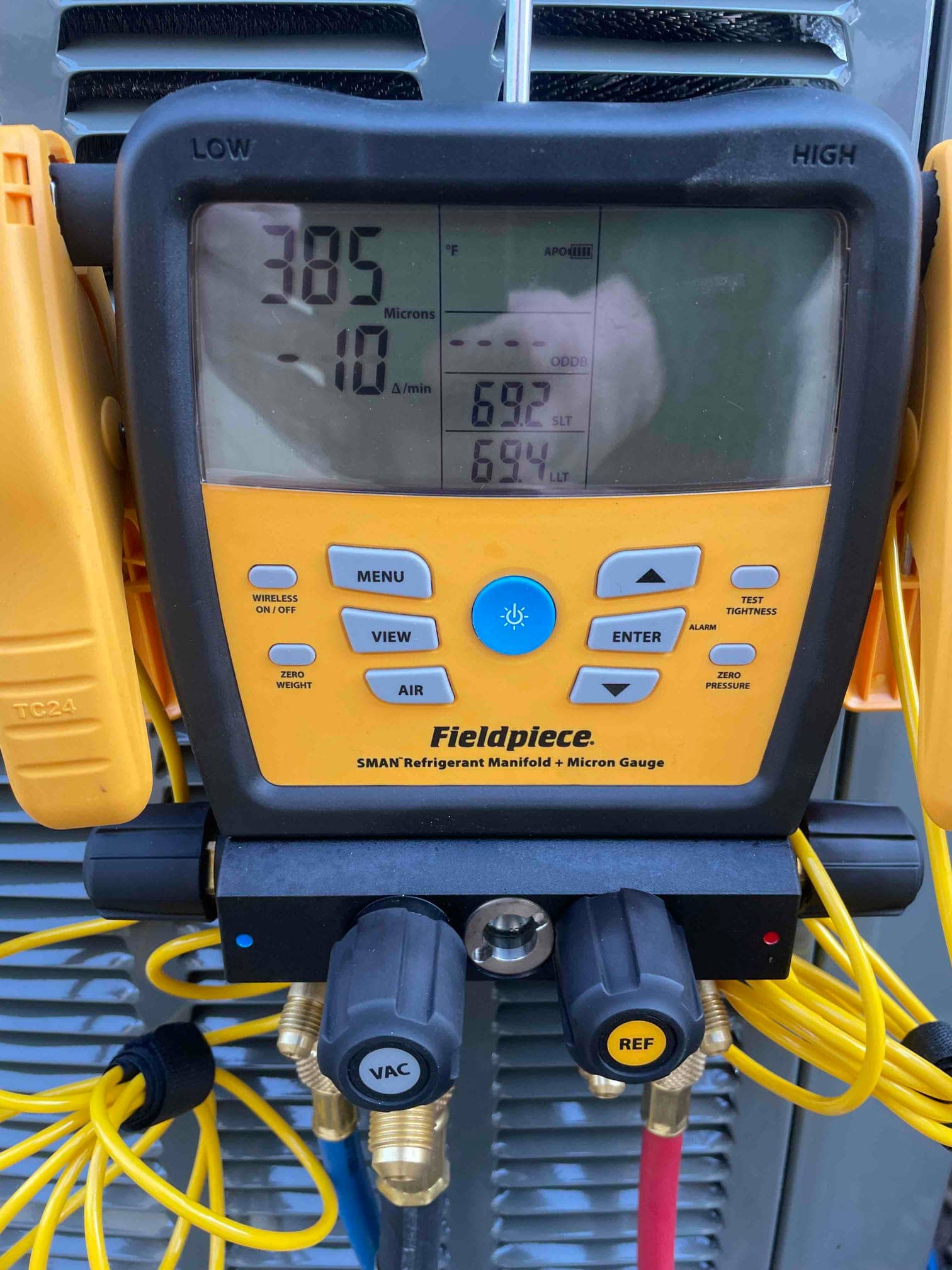Digital micron gauge shows 385 microns with decay rate, documenting deep vacuum during system evacuation before refrigerant charging.