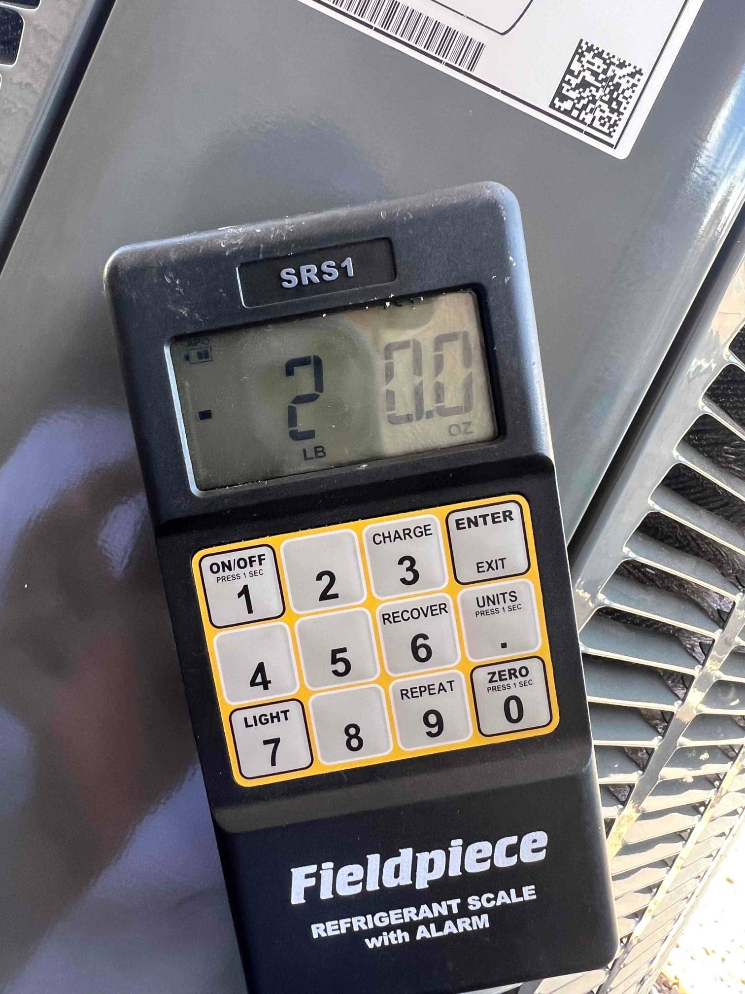 Digital refrigerant scale shows 2 pounds, 0.0 ounces during charging of the newly installed outdoor unit.