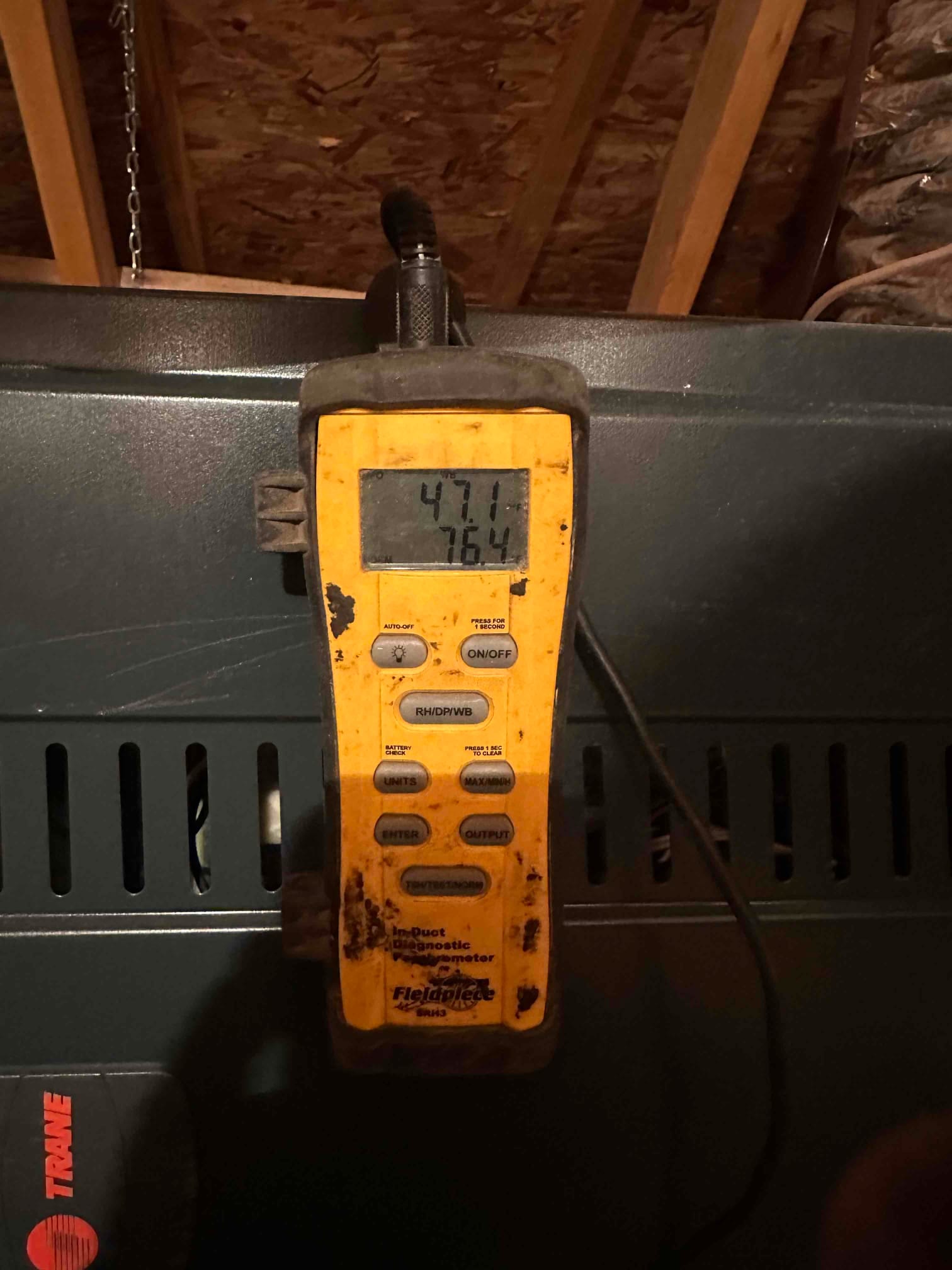Digital thermometer attached at the air handler displays 47.1 and 76.4 degrees, documenting supply and return air temperatures.