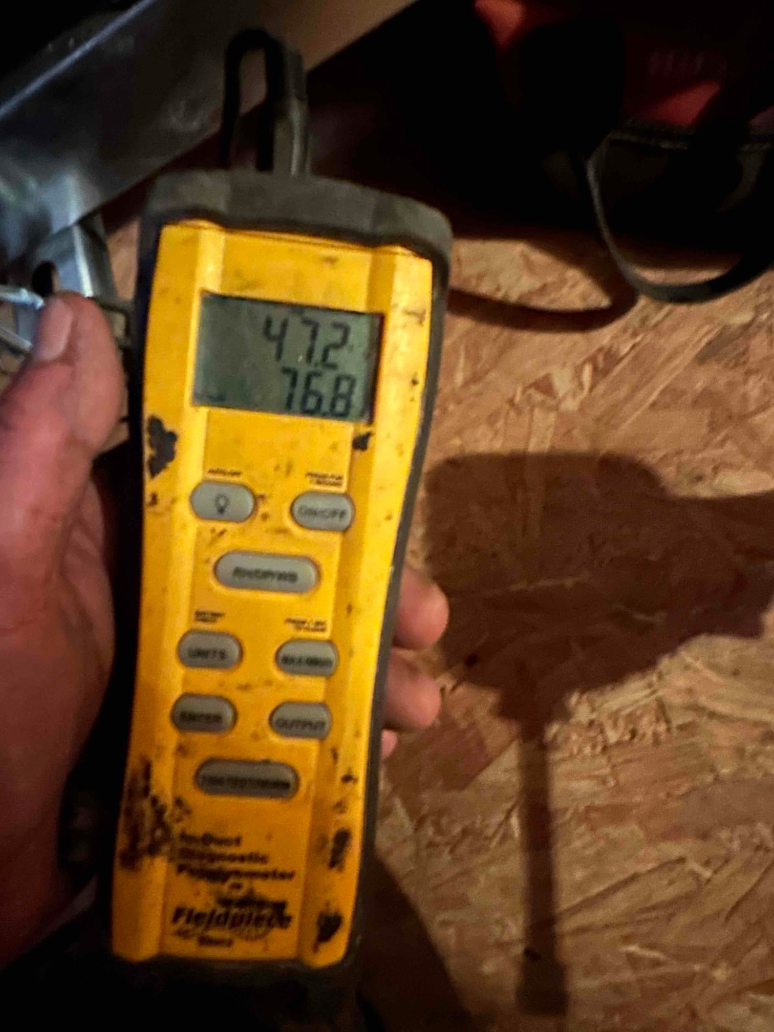Digital thermometer displays 47.2 degrees and 76.8 degrees while measuring air temperatures during system startup checks.