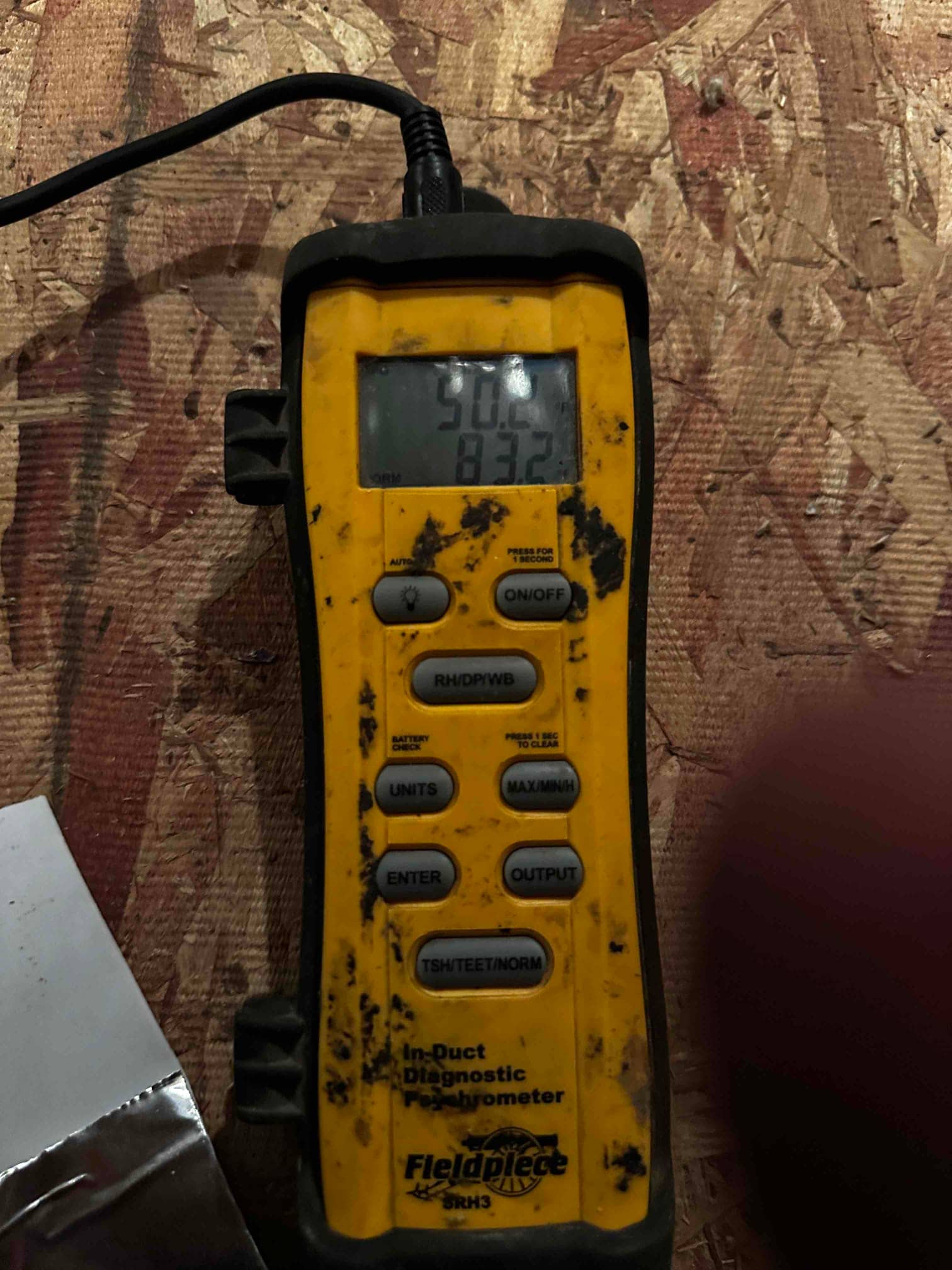 Digital thermometer shows 50.0 degrees, documenting supply air temperature during air-side commissioning of the new system.