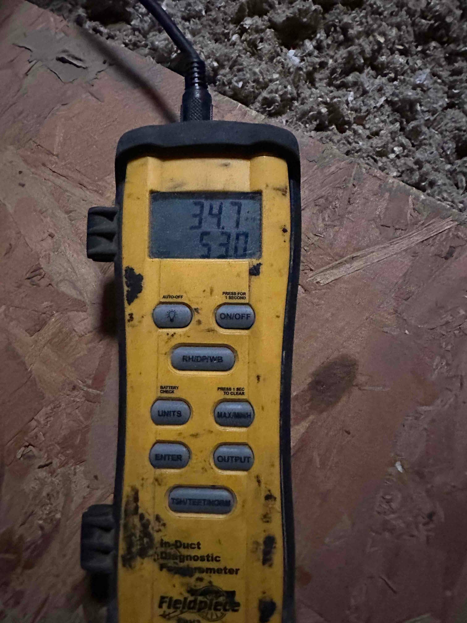Digital thermometer shows 53 degrees Fahrenheit on the lower display during air temperature measurement in the duct system.