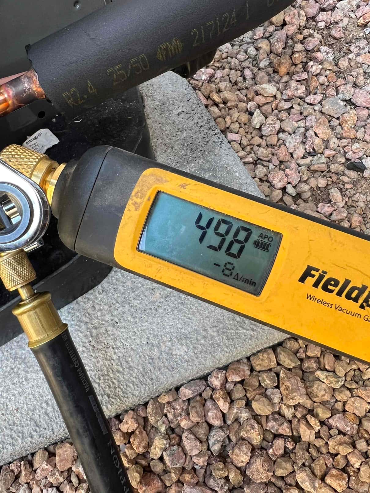 Digital vacuum gauge connected to the system shows 498 microns, confirming a deep vacuum during the evacuation phase before charging.