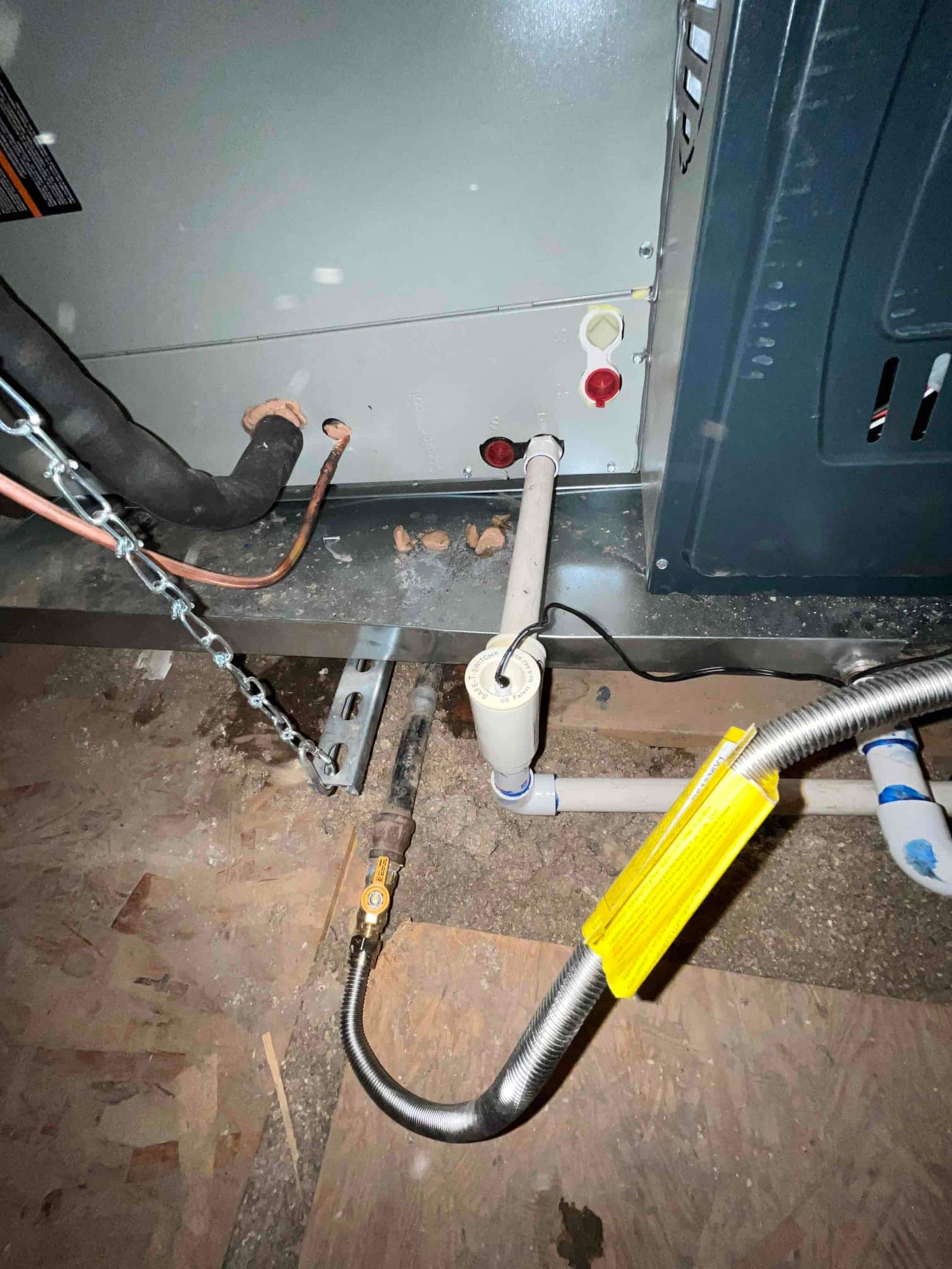 Furnace bottom connections showing condensate trap and drain, gas flex connector with shutoff valve, and insulated refrigerant lines.