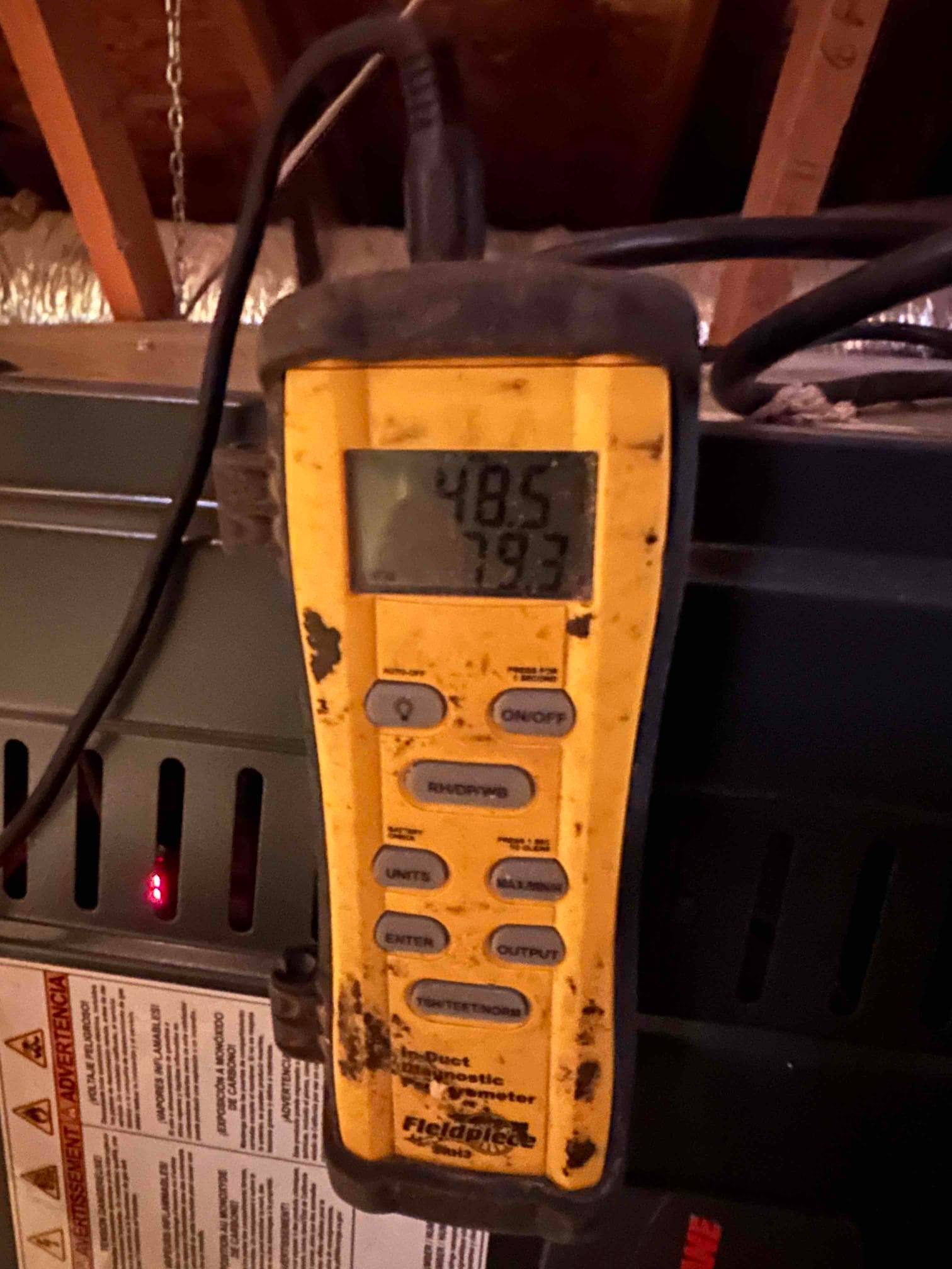 Handheld digital thermometer shows 48.5 degrees and 79.3 degrees during air temperature readings at the HVAC equipment.