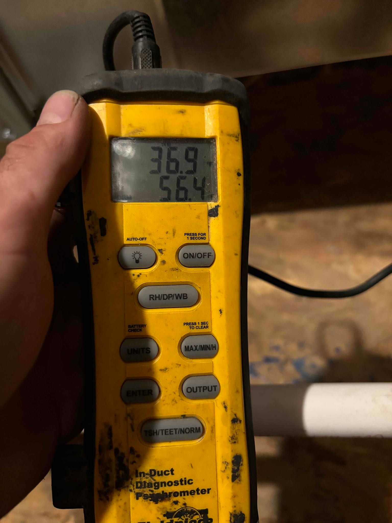 Handheld thermometer displays supply air temperature of 56.4 degrees during cooling airflow check at the new installation.