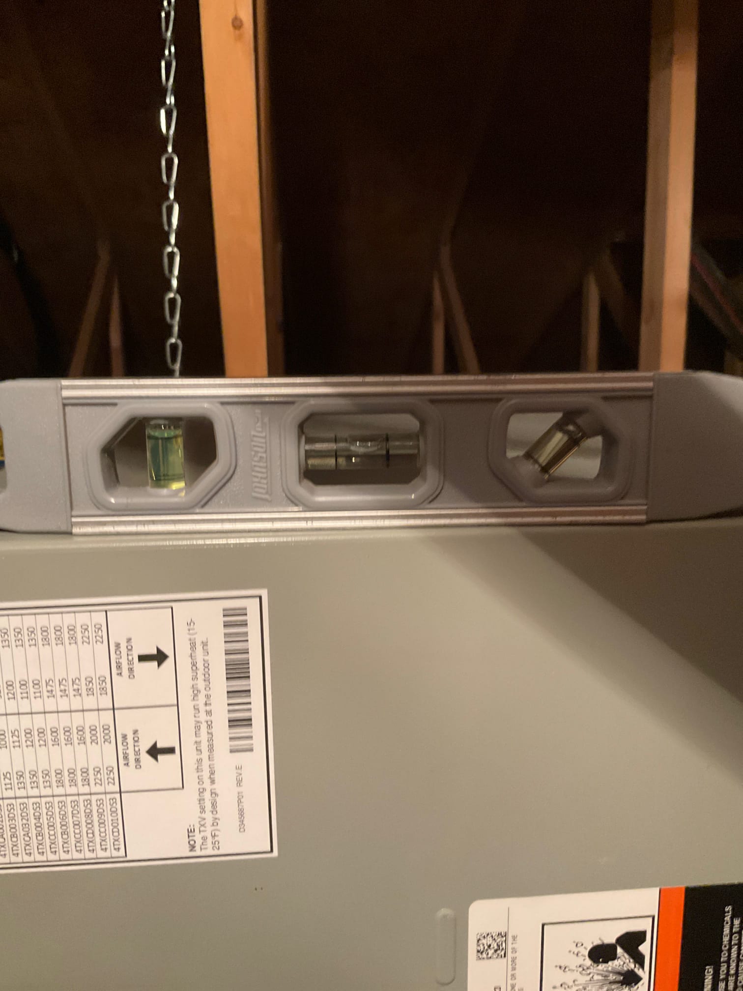 Level placed on top of an air handler cabinet in the attic to verify the unit is set level during installation.