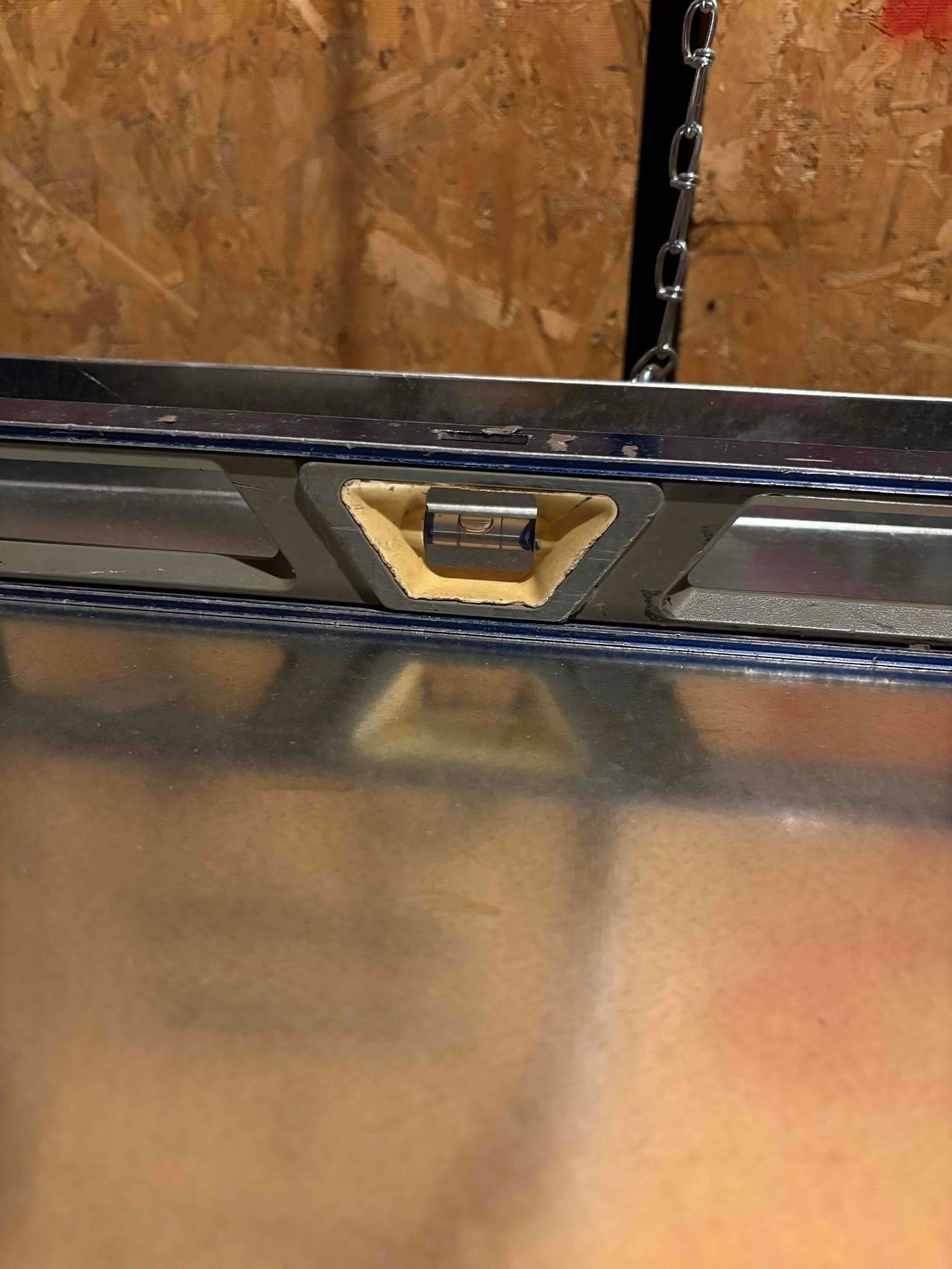 Level placed on top of sheet-metal HVAC cabinet to verify the unit is set plumb and level during installation.