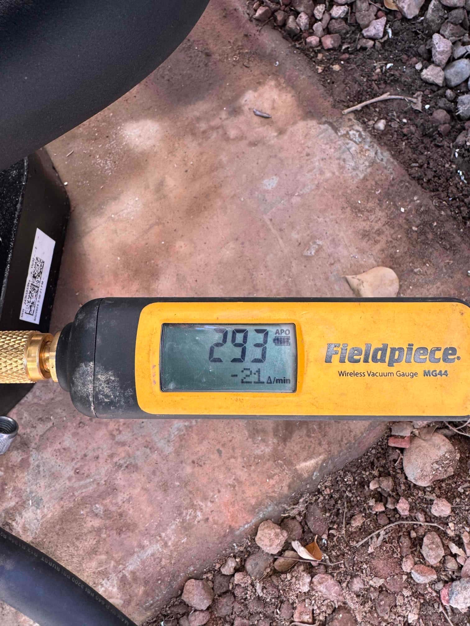 Micron gauge connected during evacuation reads 293 microns, confirming a deep vacuum before releasing refrigerant.