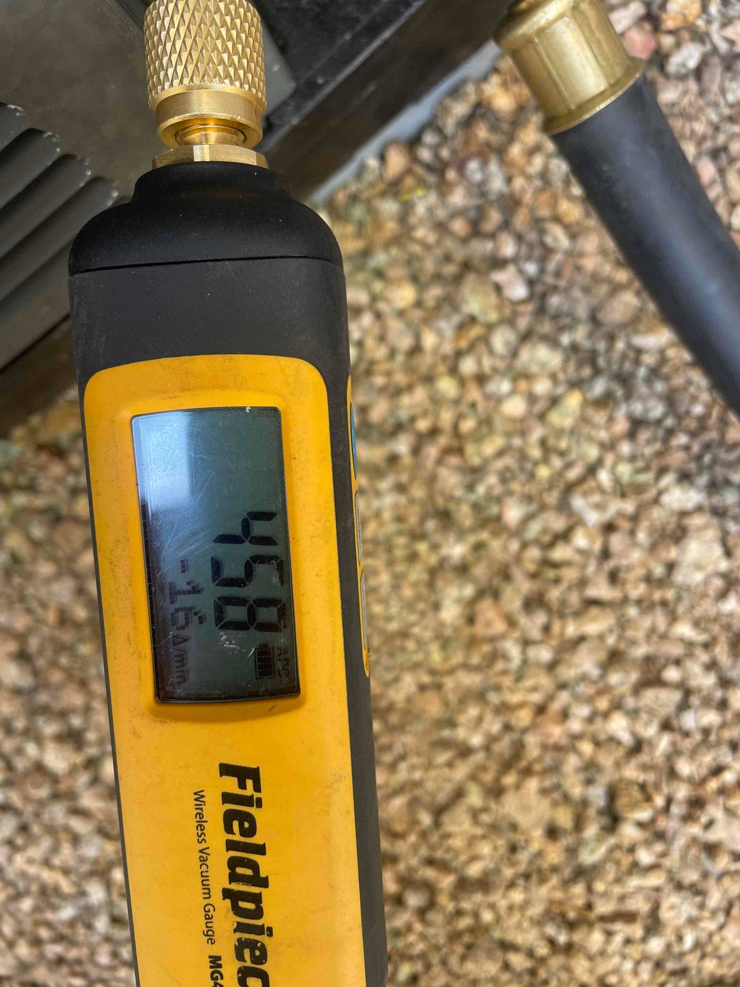Micron gauge connected at the outdoor unit reads 458 microns, confirming a deep vacuum during system evacuation.