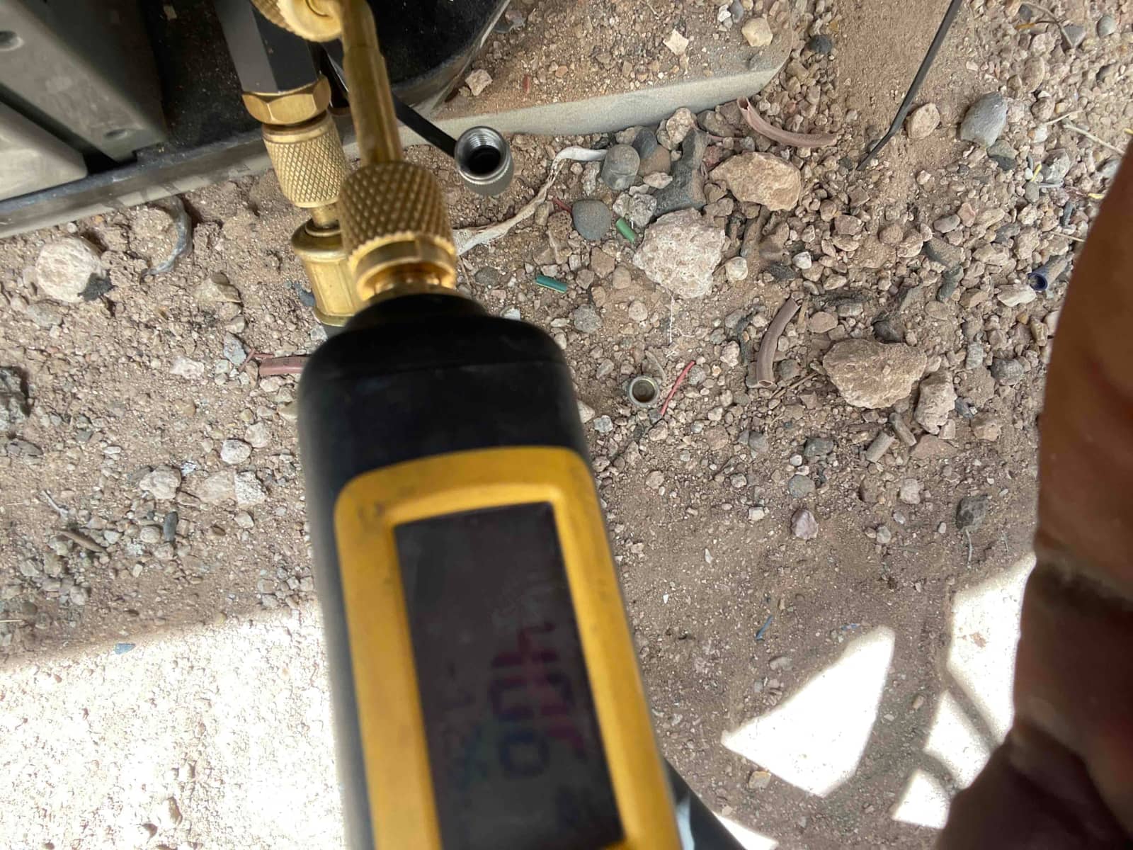 Micron gauge connected at the service port during evacuation, confirming a deep vacuum before charging the system.
