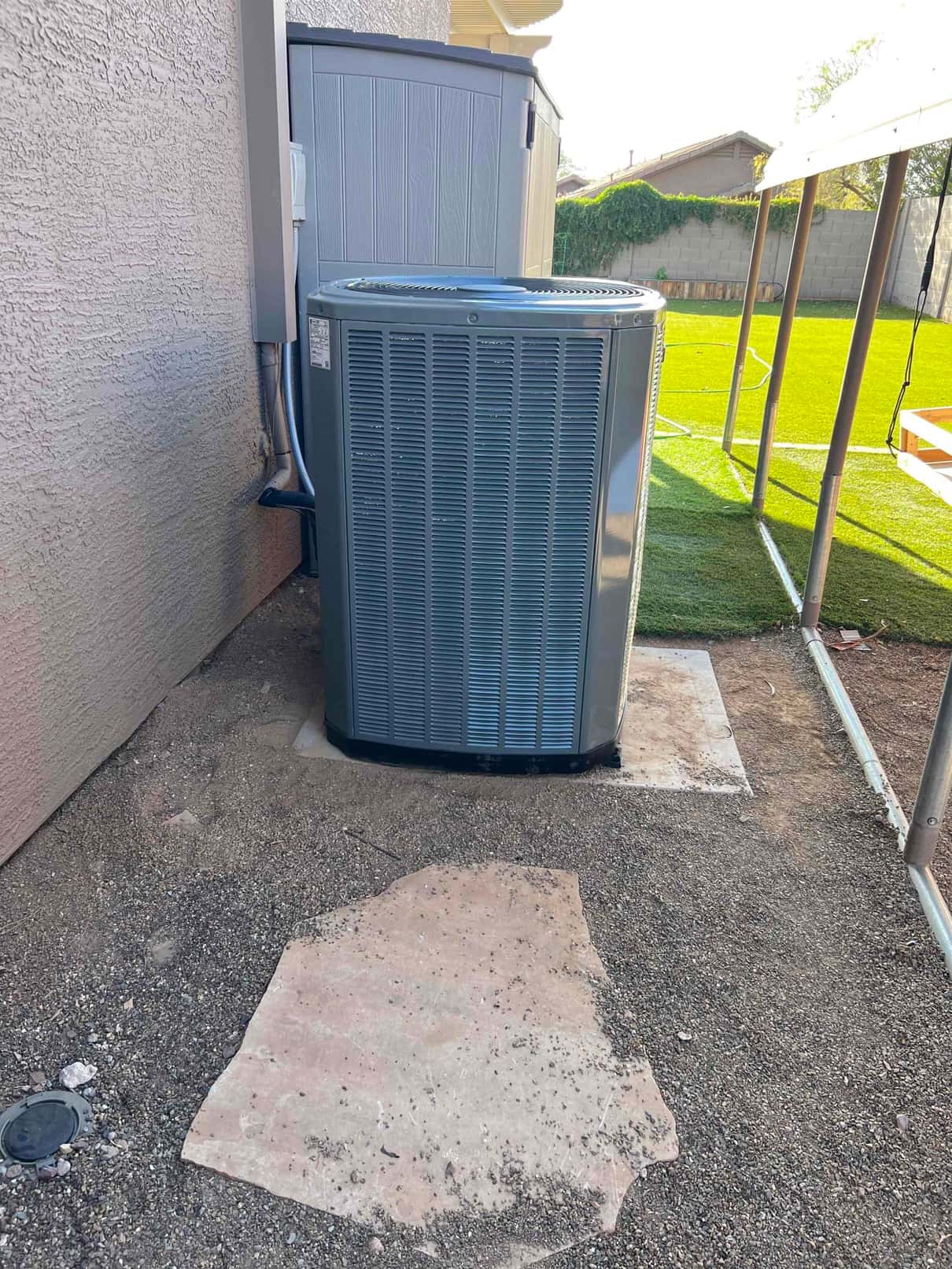 New outdoor condenser set on a concrete pad with insulated line set and electrical disconnect mounted on the wall.