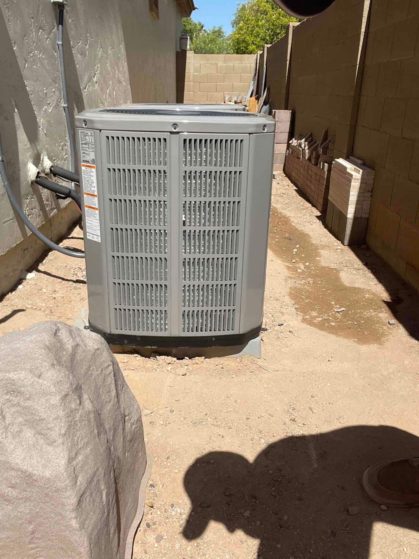 New outdoor condenser set on a level pad with insulated line set and sealed wall penetration along the side yard.