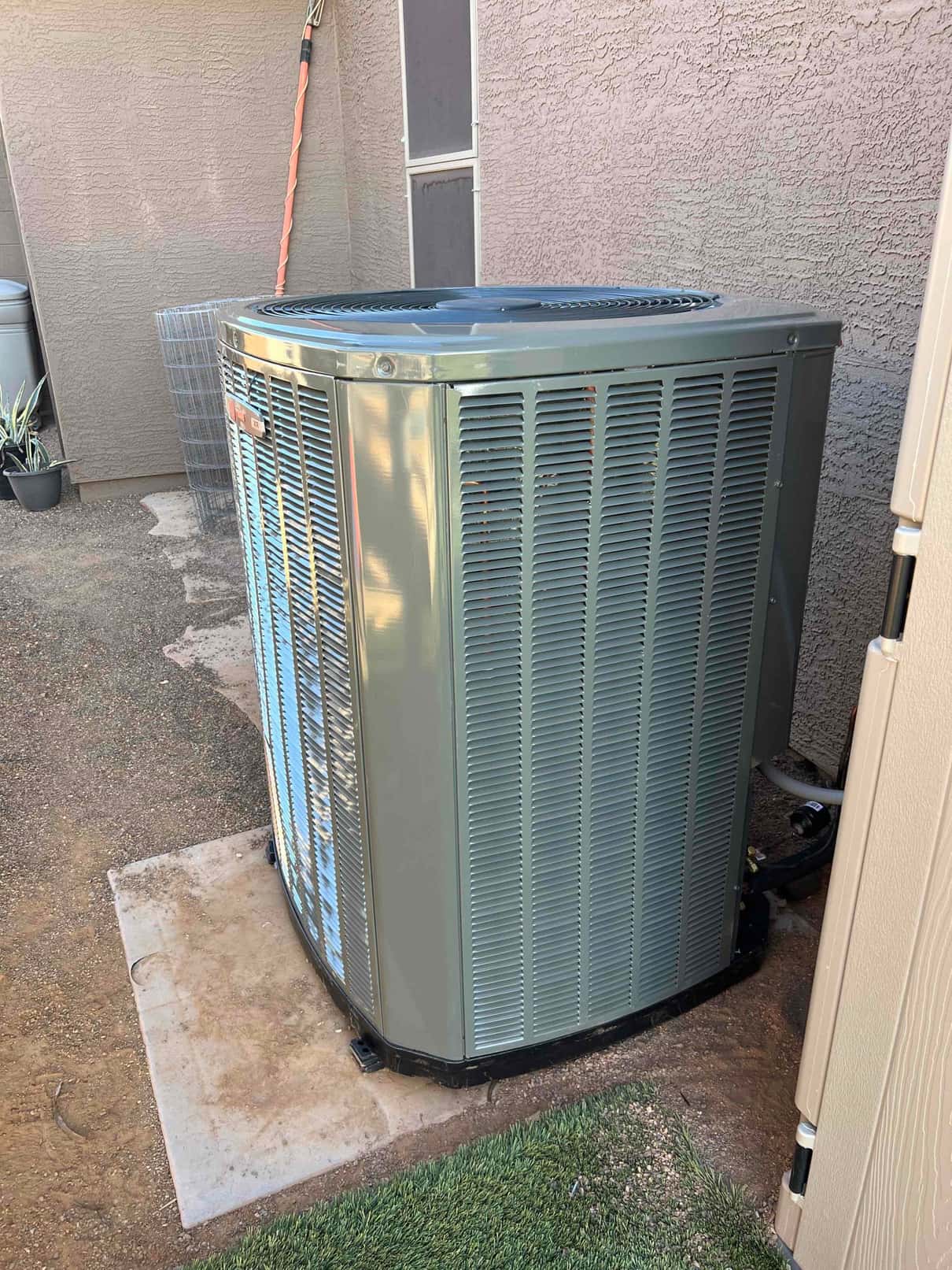 New outdoor condenser set on a level pad with insulated refrigerant lines routed to the wall penetration and service valves accessible.