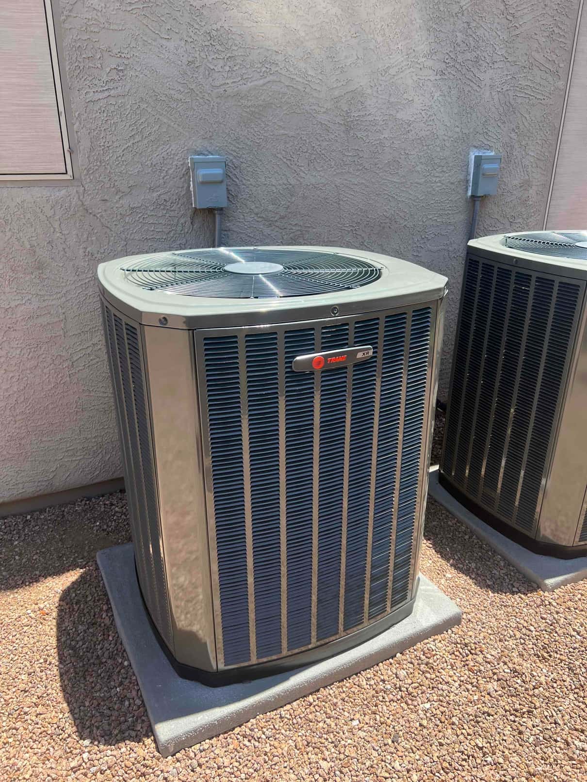 New outdoor condenser set on a level pad with nearby electrical disconnects mounted on the wall.