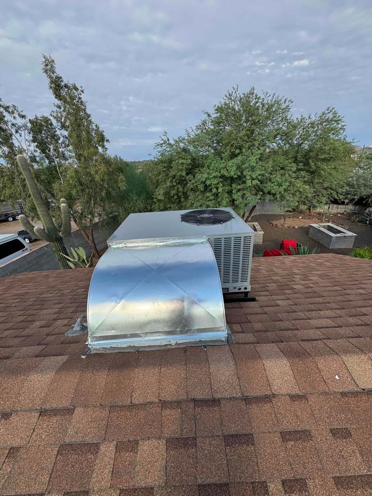 New rooftop package unit installed on shingles with sheet-metal roof curb and sealed duct transition visible.