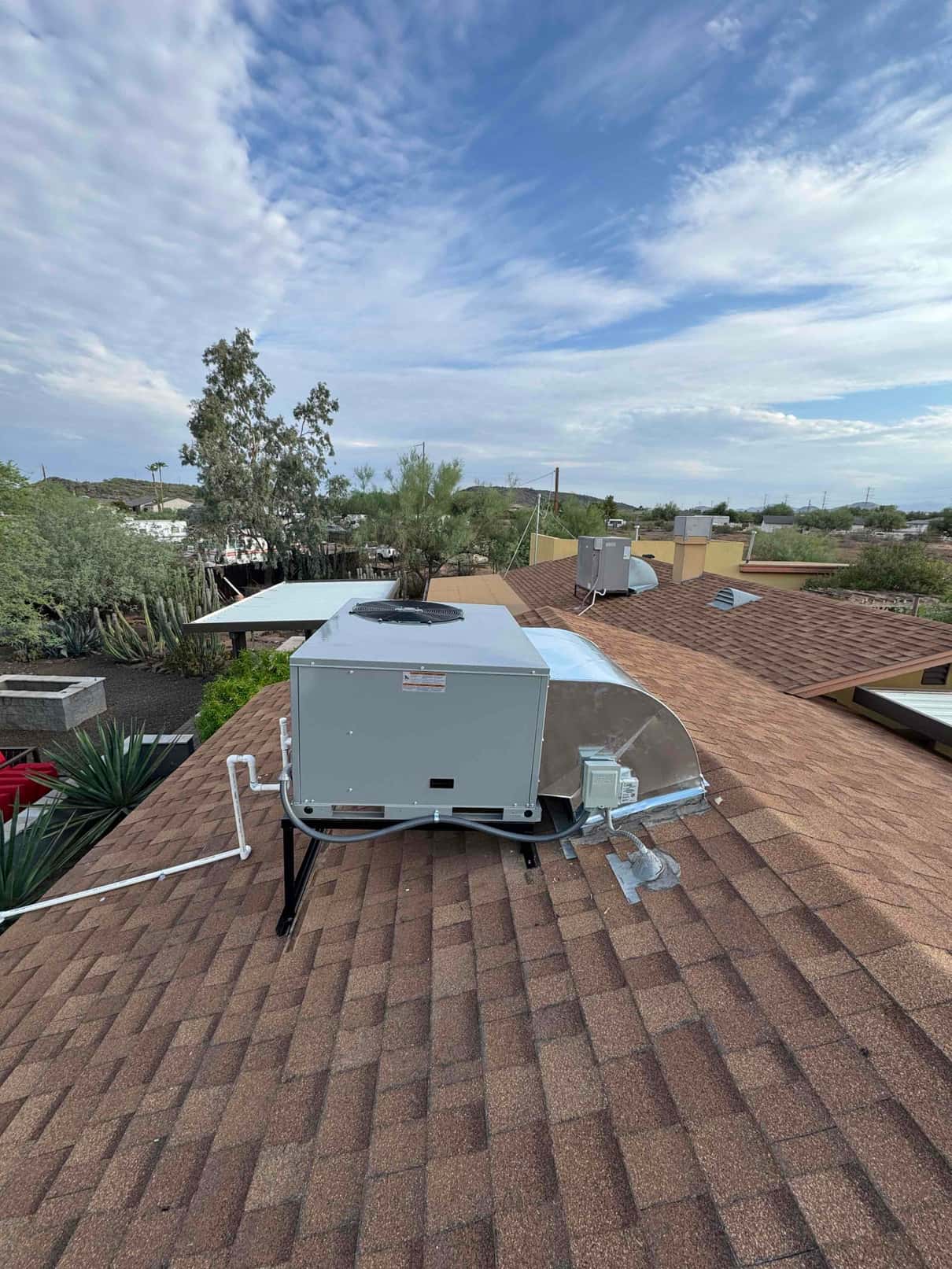 New rooftop package unit installed on stands with insulated condensate drain, sealed curb adapter, and weatherproof electrical disconnect.