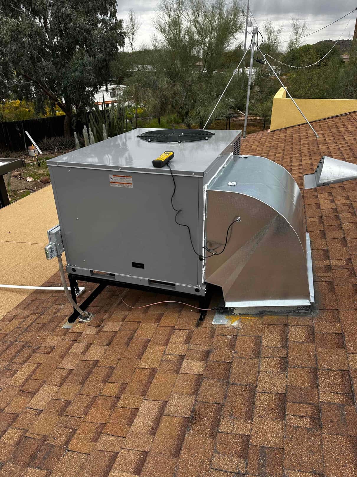 New rooftop package unit set on a stand with sealed curb and connected duct transition during installation.