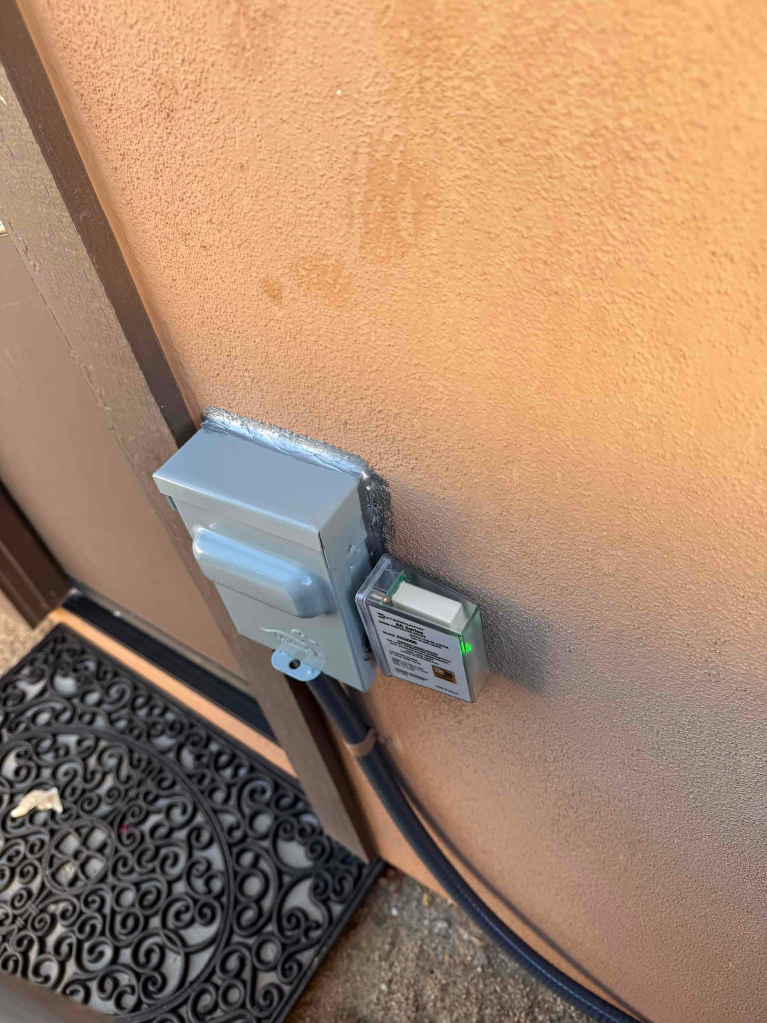 Outdoor AC disconnect and surge protector mounted on exterior wall with sealed conduit routing to the condenser.
