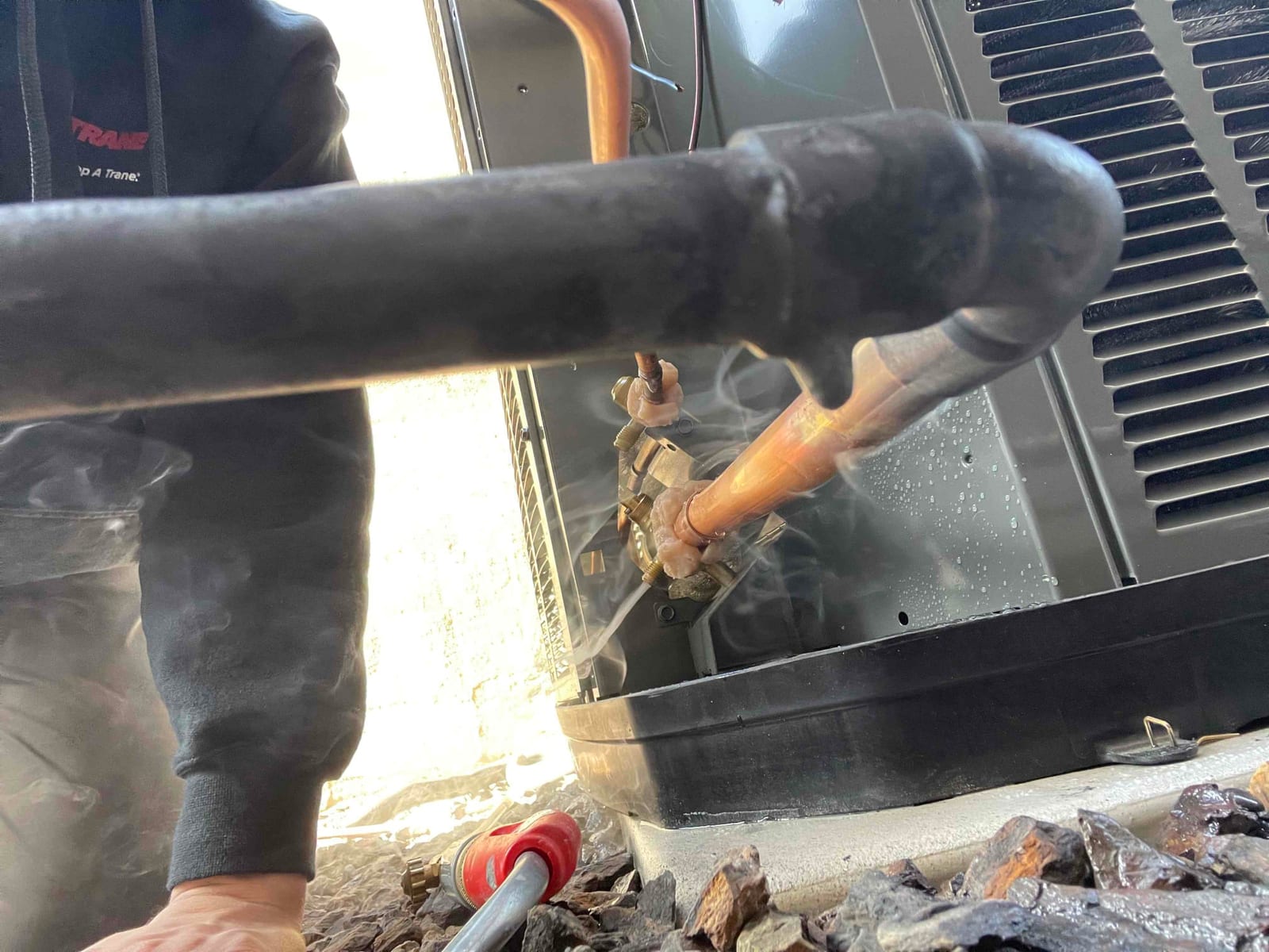 Outdoor condenser line set connections with soap bubbles applied for leak check at brazed joints during installation.