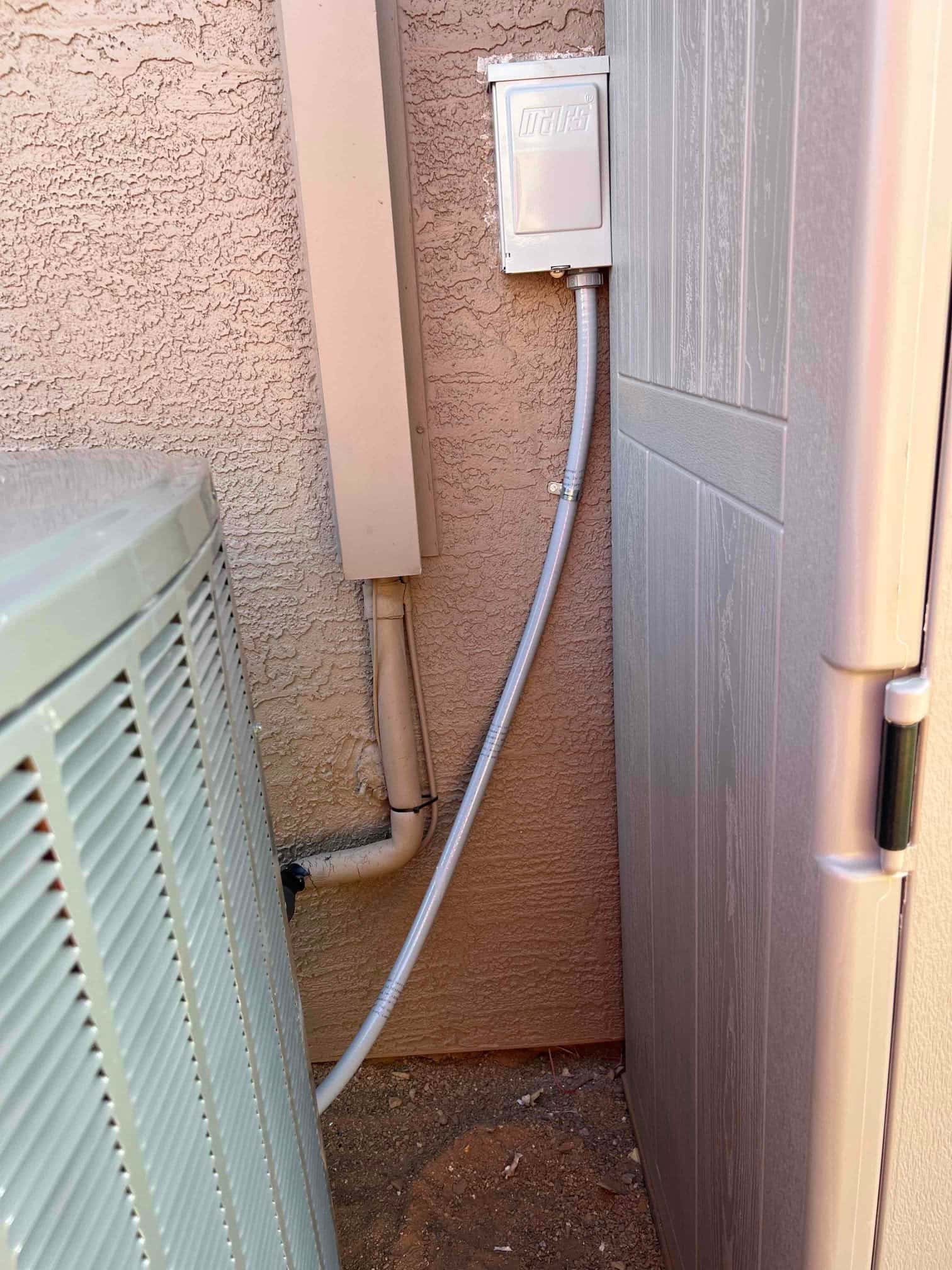 Outdoor condenser next to wall with sealed line set cover, new electrical disconnect, and flexible conduit neatly routed.