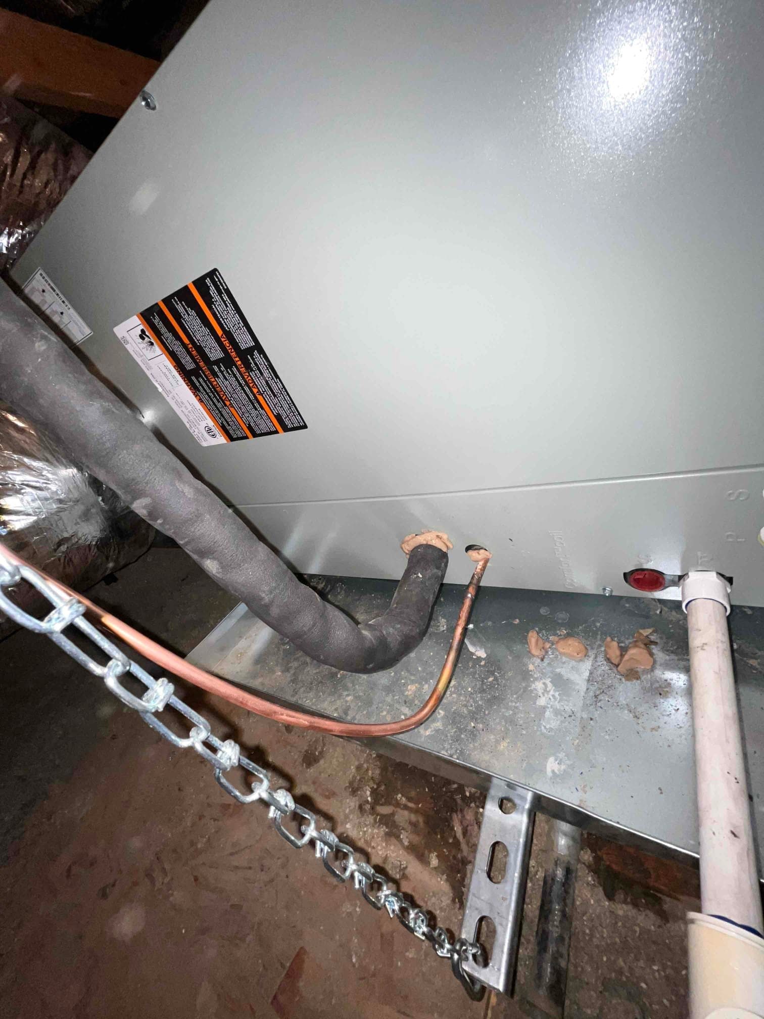 Refrigerant lines, condensate drain, and sealed penetrations connect to the new air handler on a suspended platform.