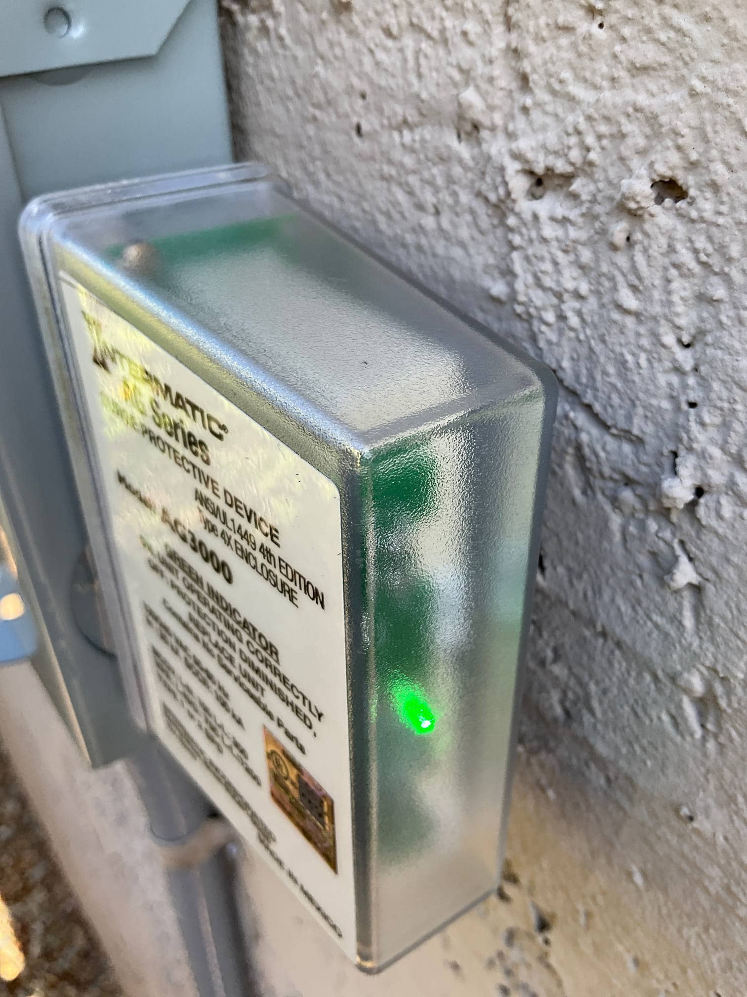 Surge protective device mounted at the outdoor disconnect with green status indicator illuminated, showing protection is active.
