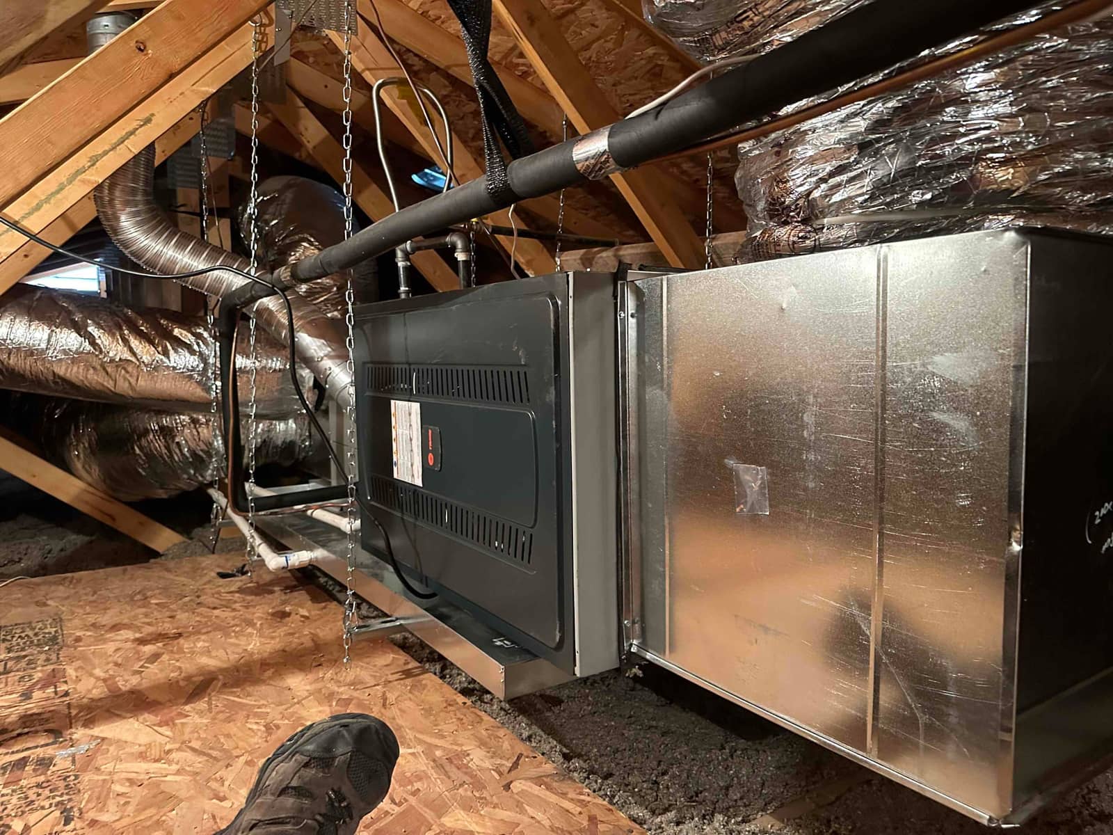 Suspended air handler with new duct connections, insulated refrigerant lines, and condensate drain installed in the attic.