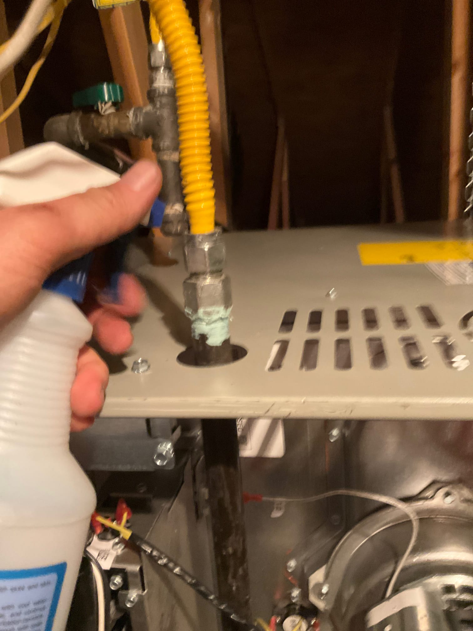 Technician sprays leak solution on the gas flex connector and fittings at the furnace to check for bubbles.
