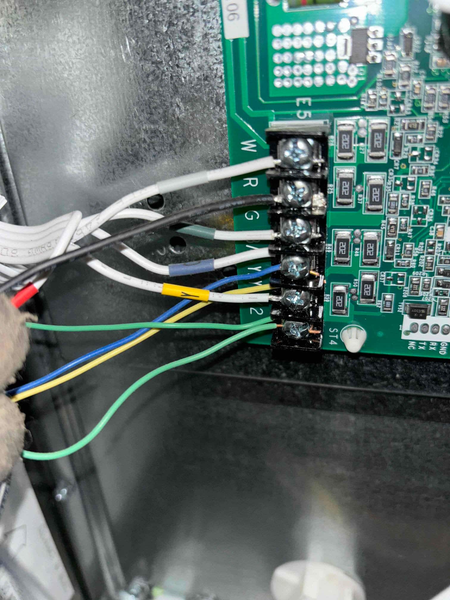 Thermostat and control wiring landed on a furnace control board terminal strip, showing R, W, G, B, and Y connections secured.