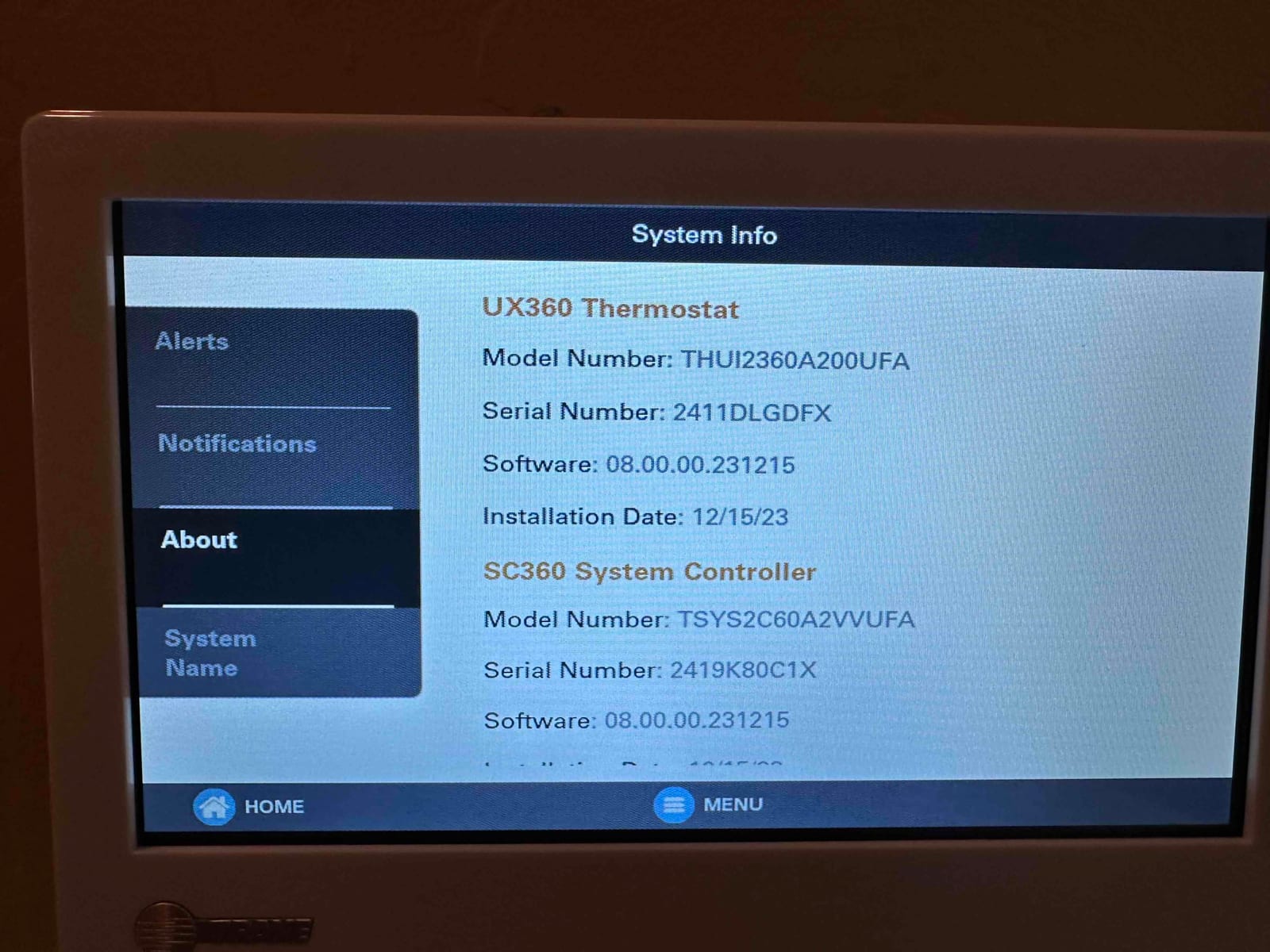 Thermostat touchscreen displays system information and menus, showing software details and installation date for the control system.