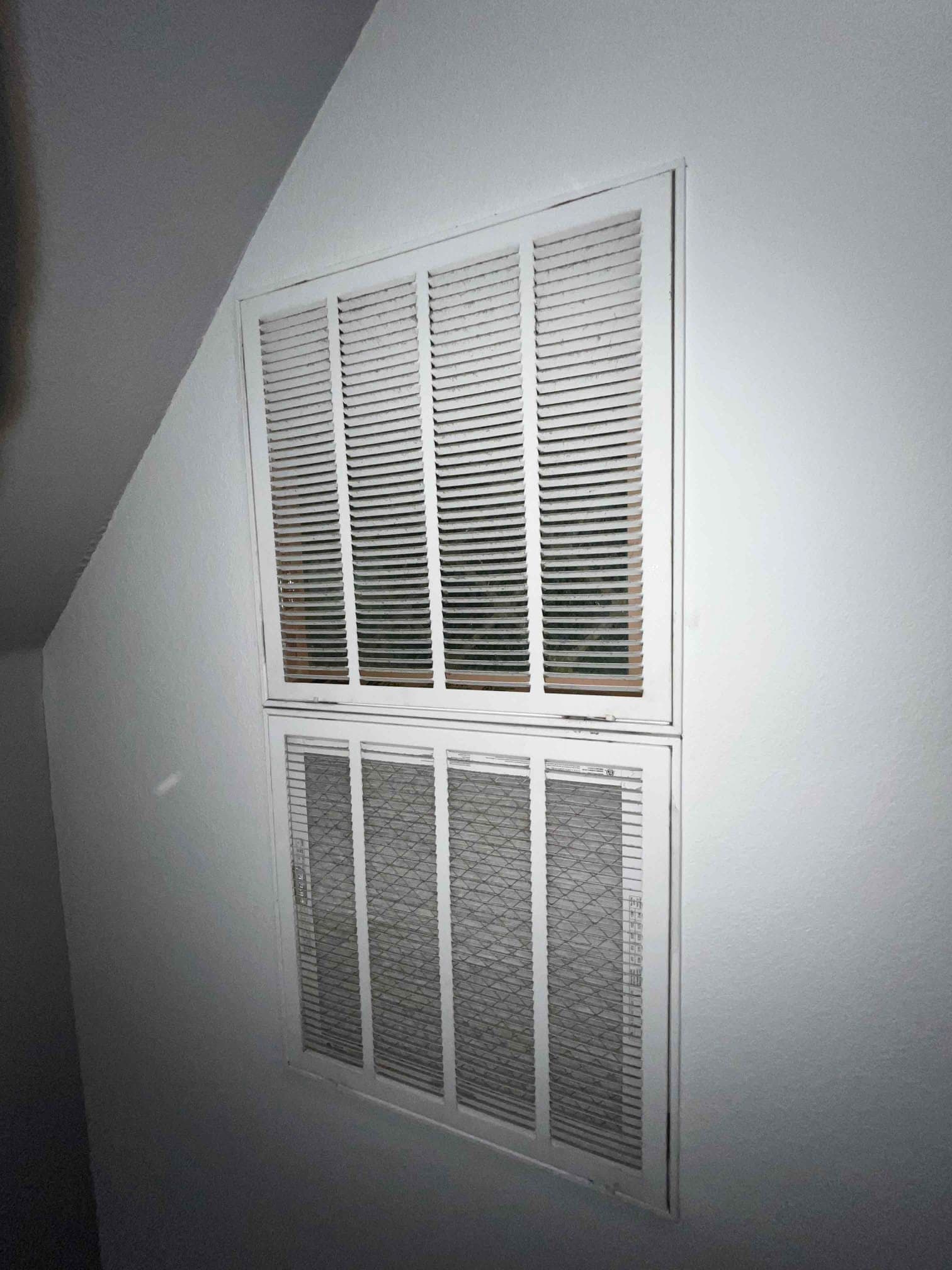 Wall-mounted return air grille assembly with double sections installed flush to the drywall during HVAC installation.
