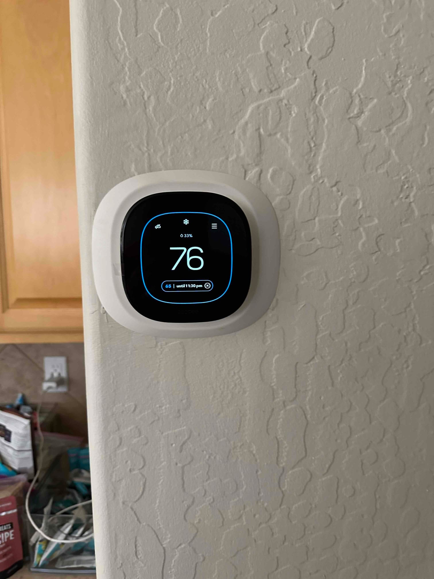 Wall-mounted smart thermostat displays a cooling setpoint with room temperature reading 76 degrees after installation.