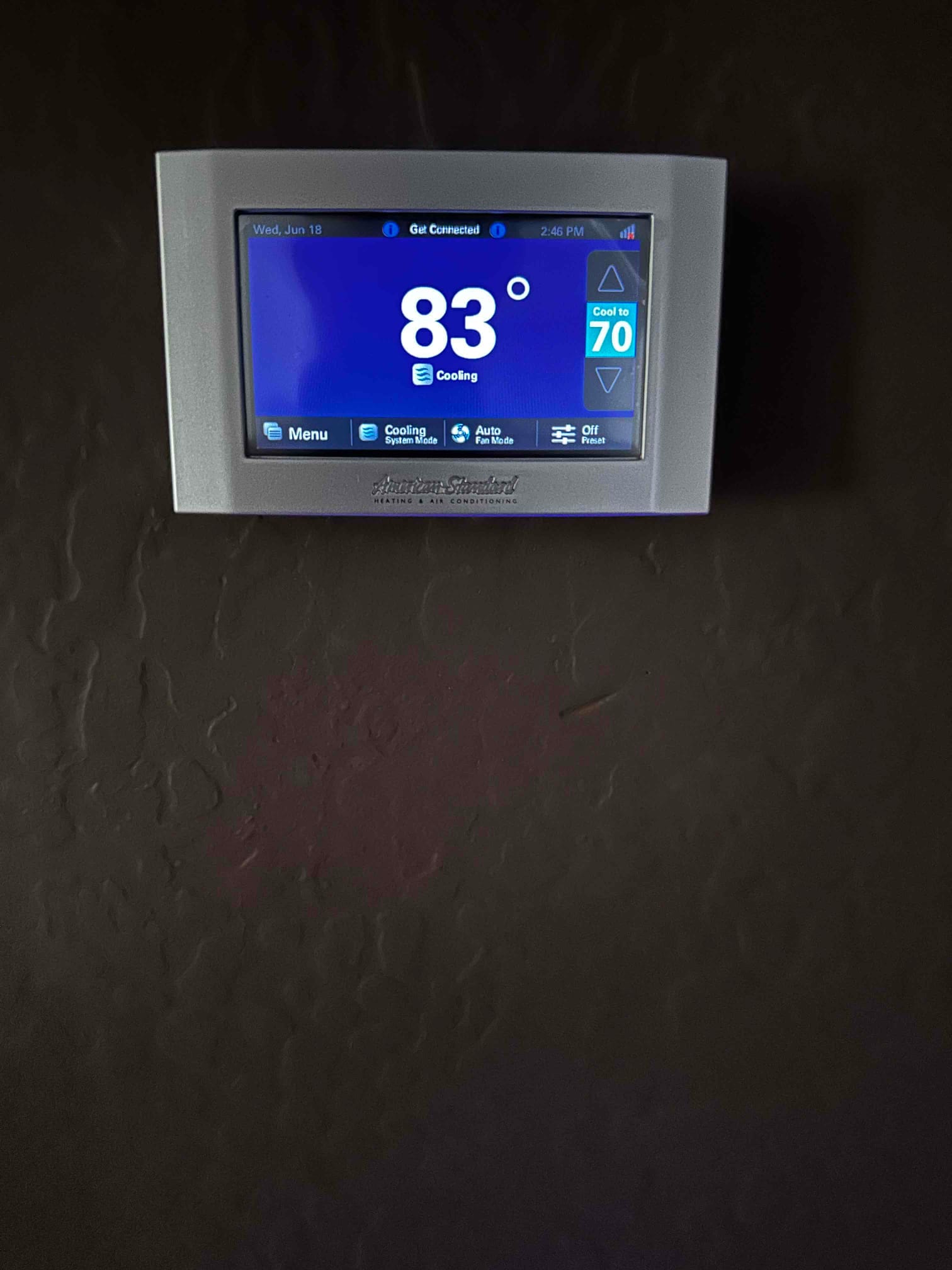 Wall-mounted thermostat displays indoor temperature of 83 degrees with system set to cool to 70.