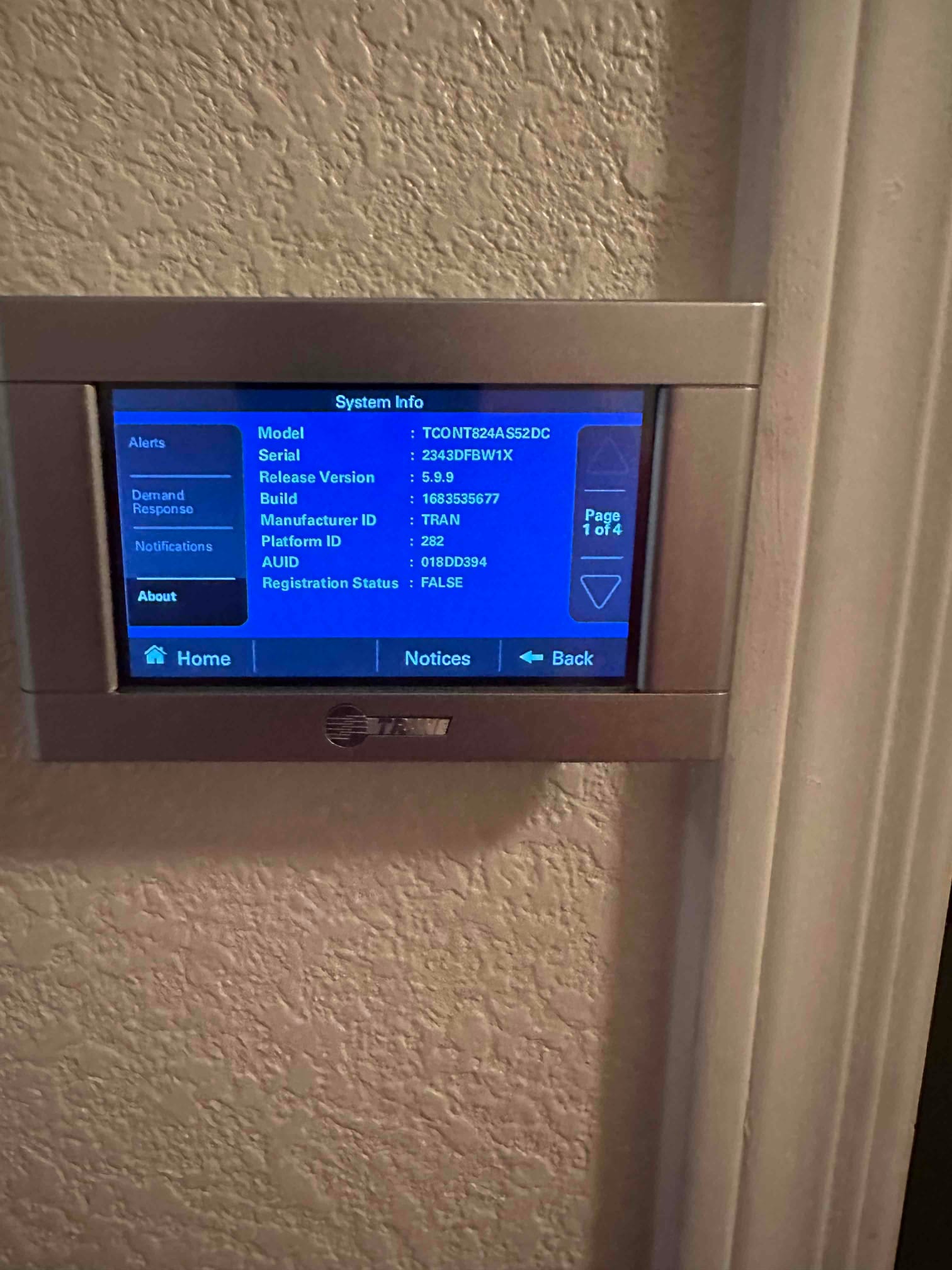 Wall-mounted thermostat displays system information screen after installation, showing menu navigation and status options for the control.