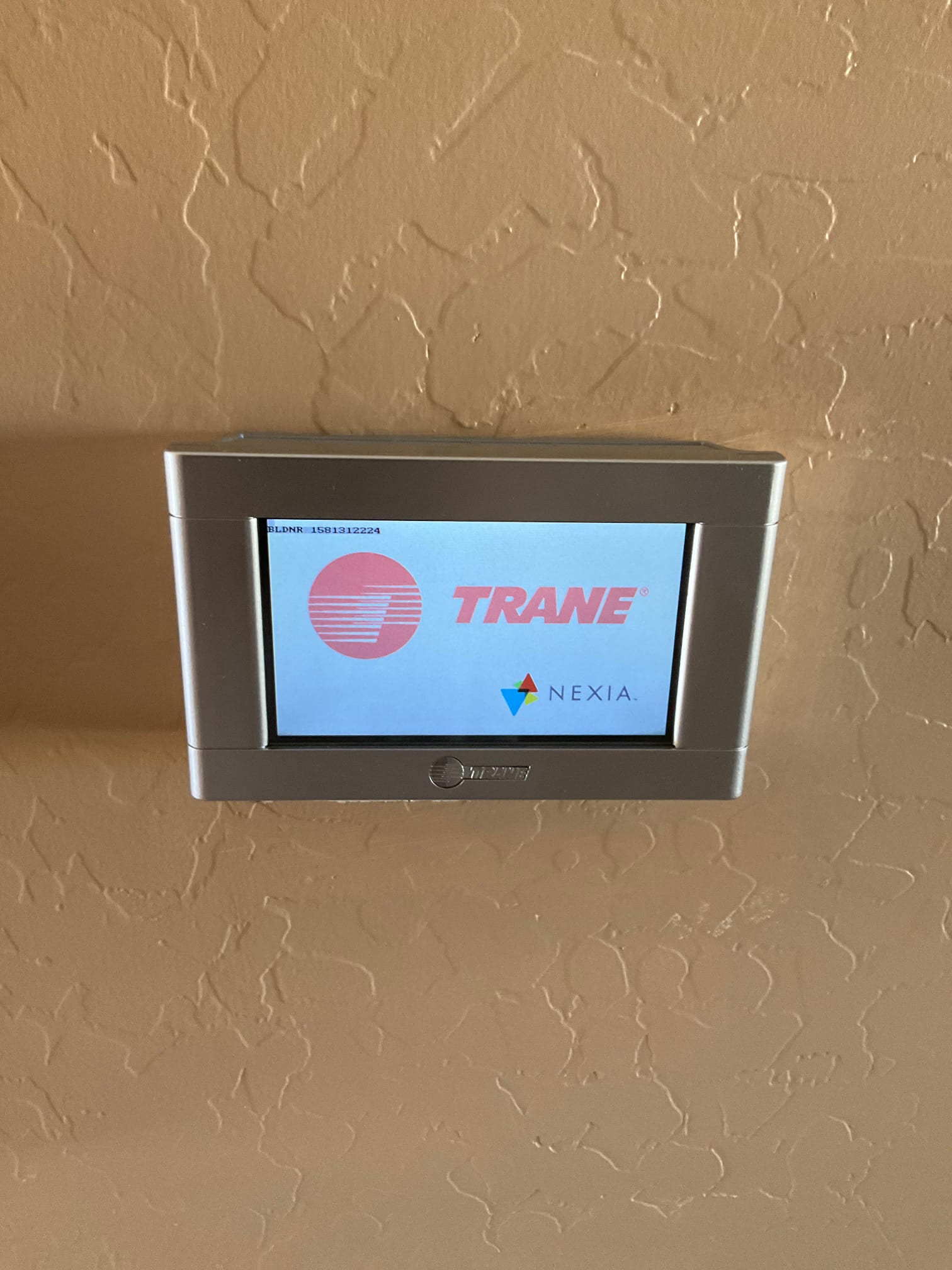 Wall-mounted touchscreen thermostat powers on, displaying startup screen after installation and setup at the HVAC system control location.