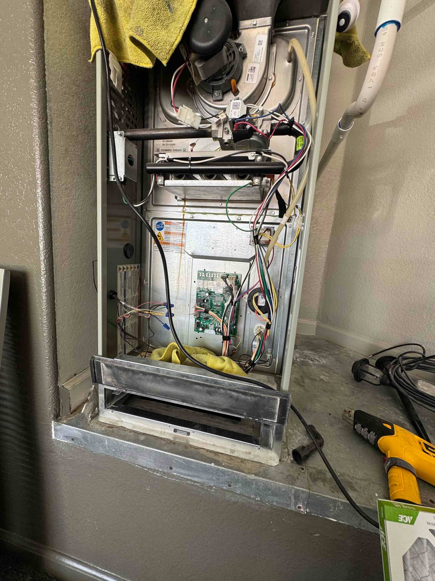 Air handler cabinet open, showing control board, wiring, blower housing, and condensate drain during evaporator coil and blower service.
