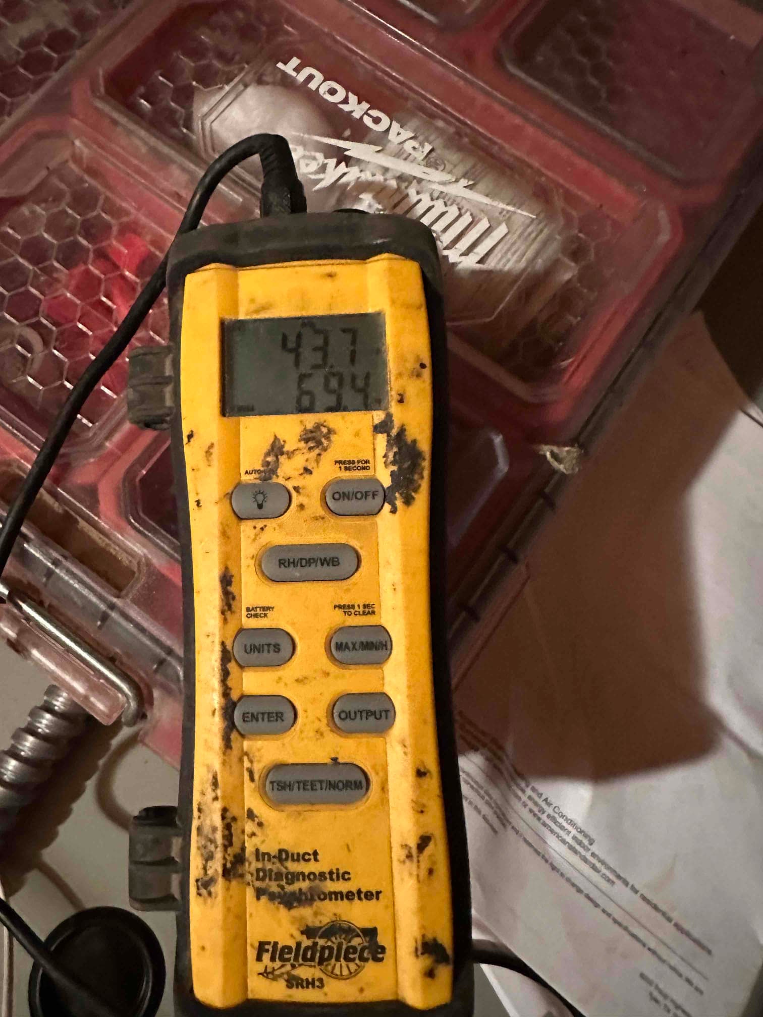 Digital in-duct thermometer displays 43.7 and 69.4 degrees, documenting air temperature measurements during system commissioning.