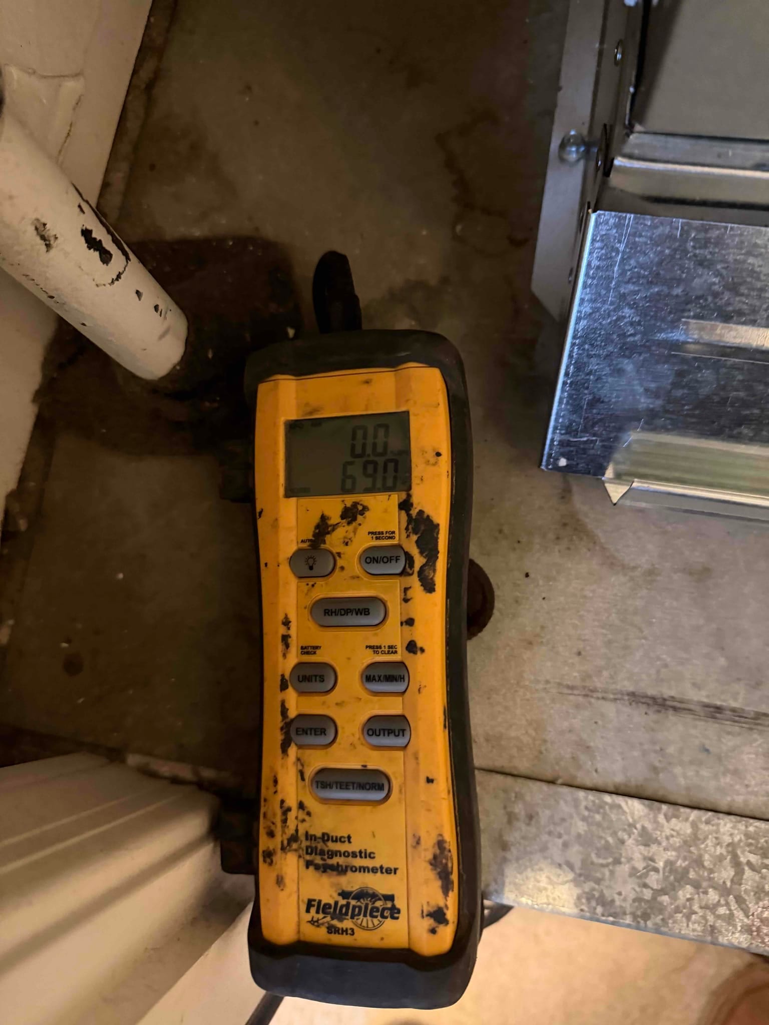 Digital in-duct thermometer shows 69.0 degrees Fahrenheit during air temperature measurement at the system.