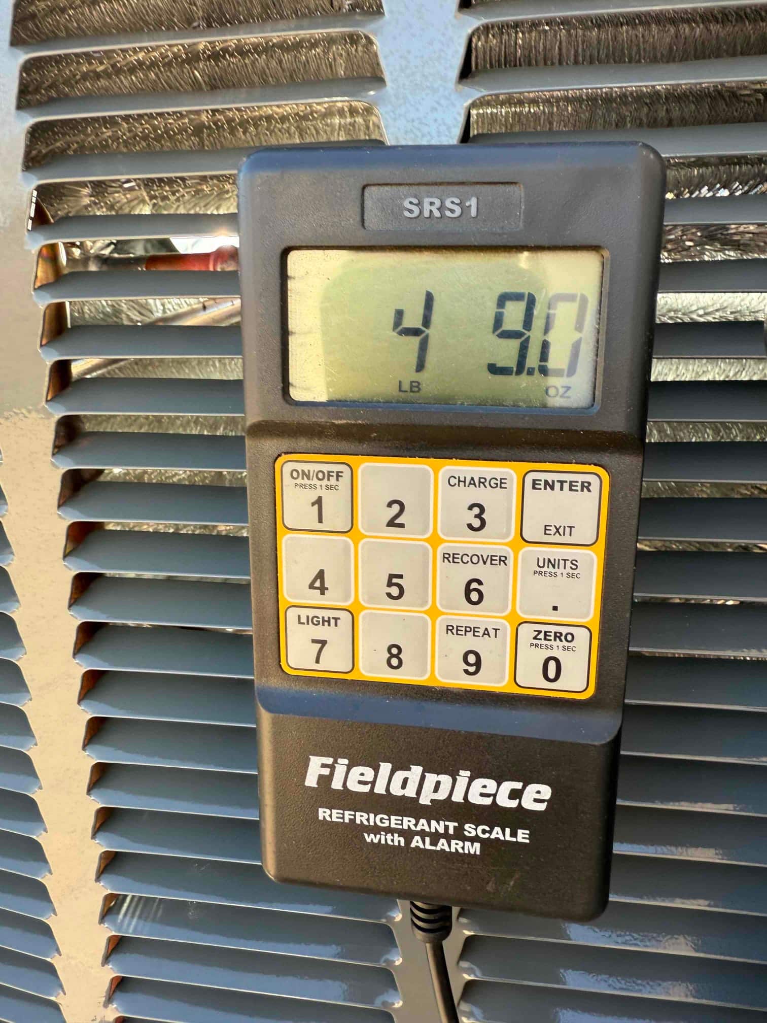 Digital refrigerant scale on the outdoor unit displays 4 pounds 9.0 ounces during refrigerant charging.