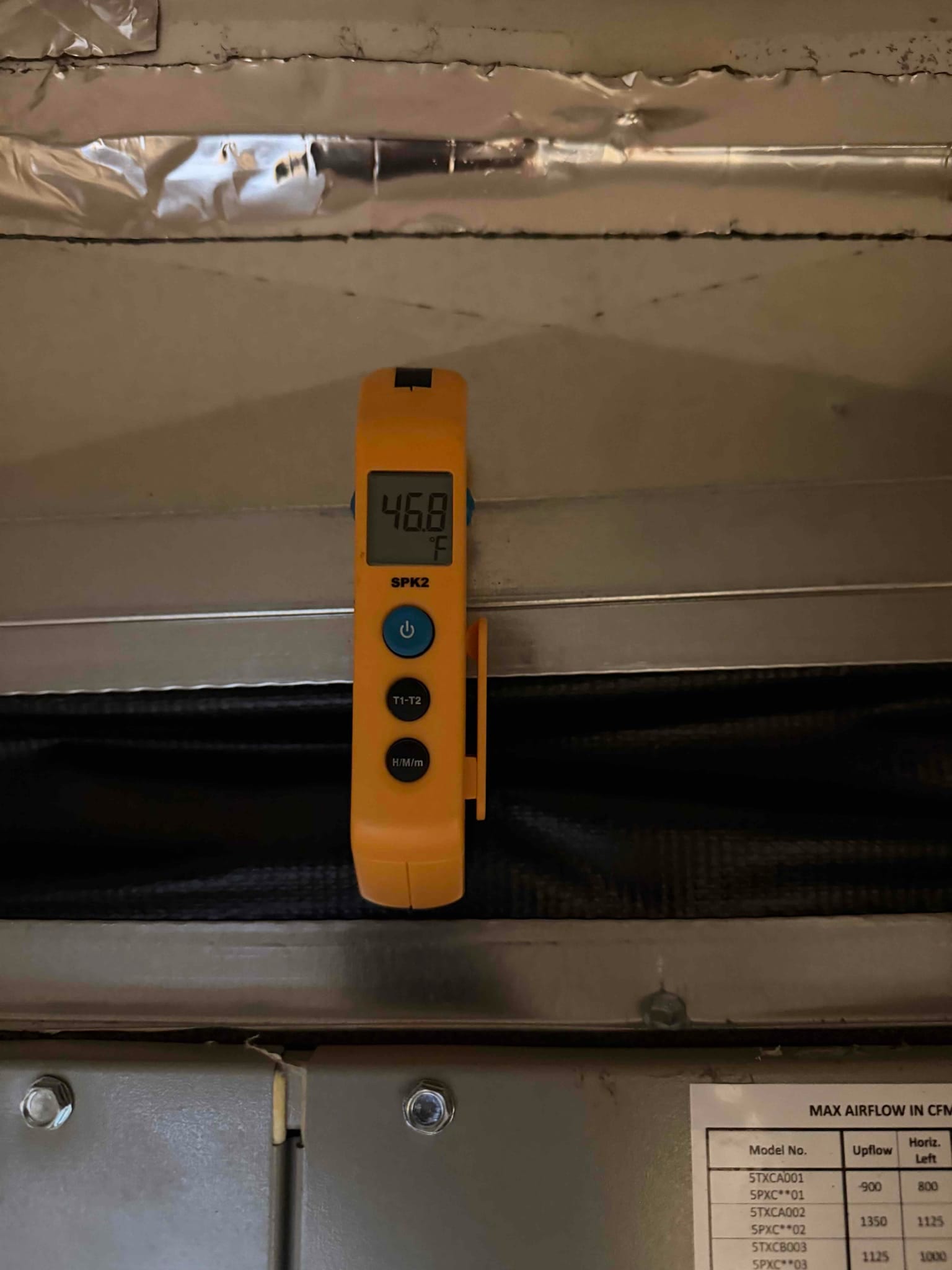 Digital thermometer placed at the supply plenum reads 46.8°F, documenting cold air temperature leaving the evaporator.