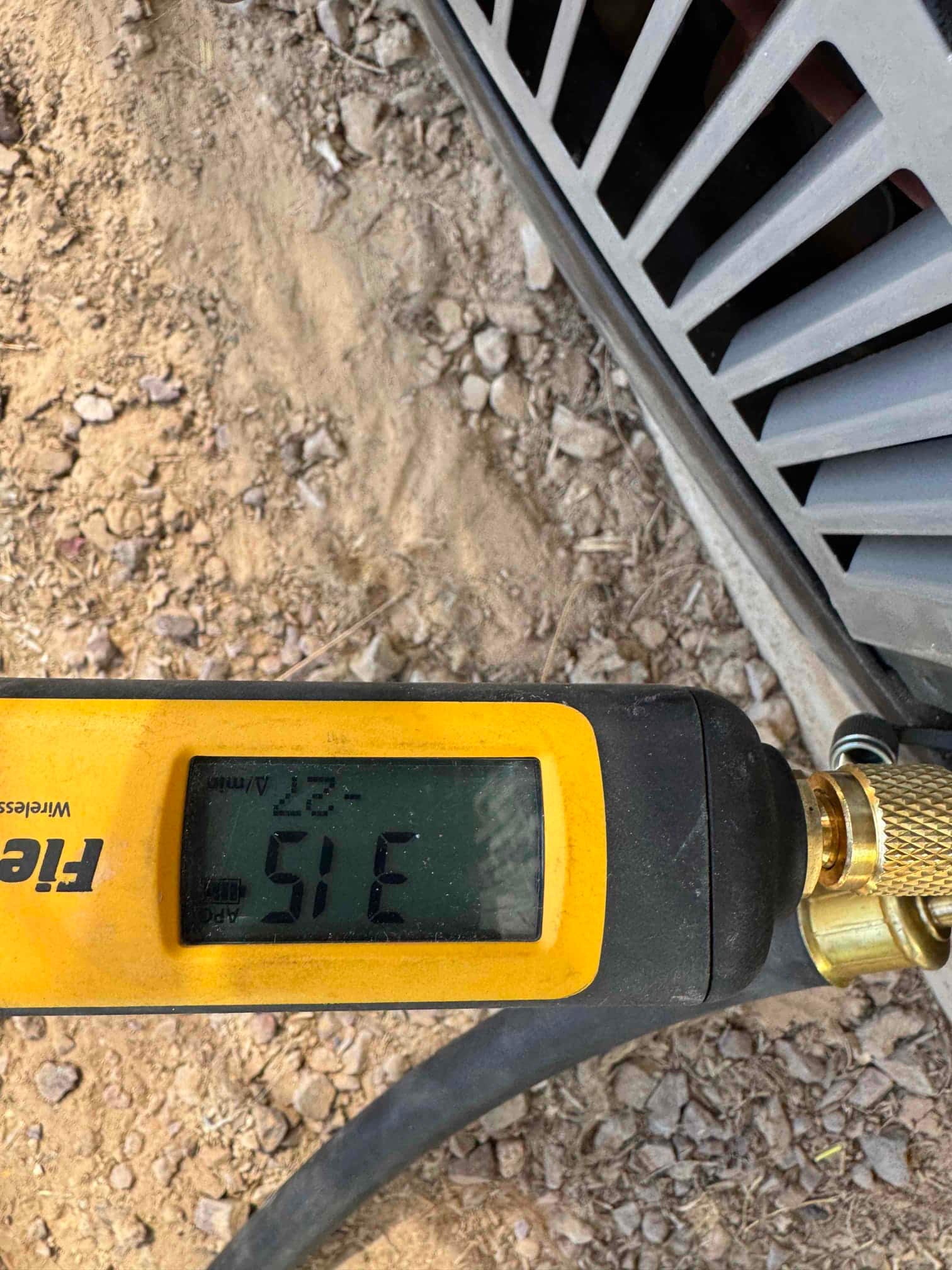 Digital thermometer probe displays 51°F while measuring air at the outdoor unit during commissioning.