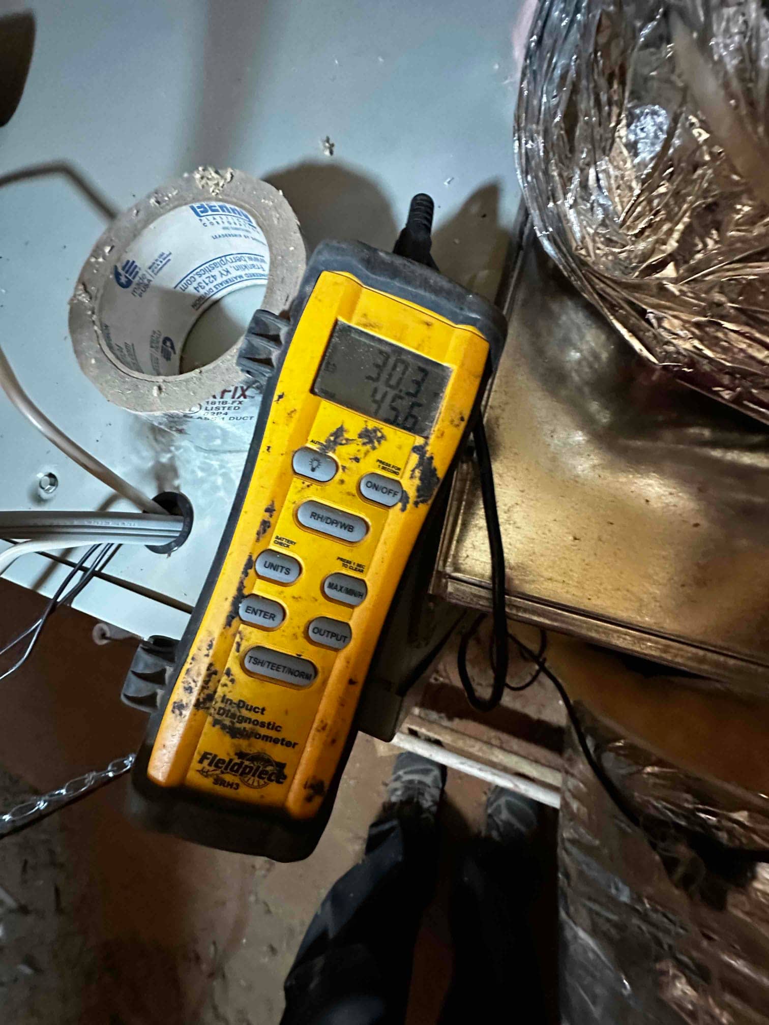 Digital thermometer probe measures air temperature at the duct, displaying readings of 30.3 and 45.6 degrees on the screen.