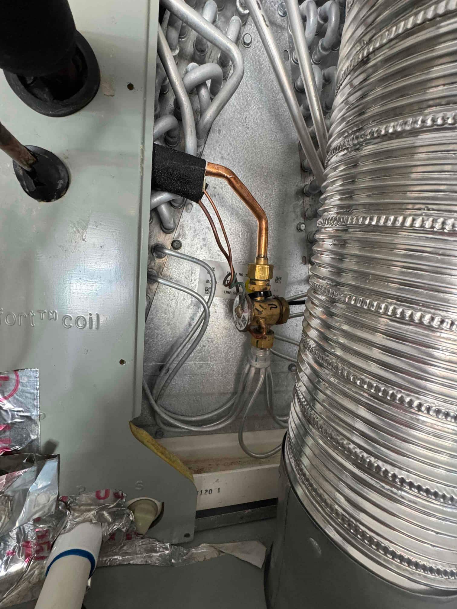 Evaporator coil compartment with thermal expansion valve, copper refrigerant lines, and insulated suction line inside the air handler.