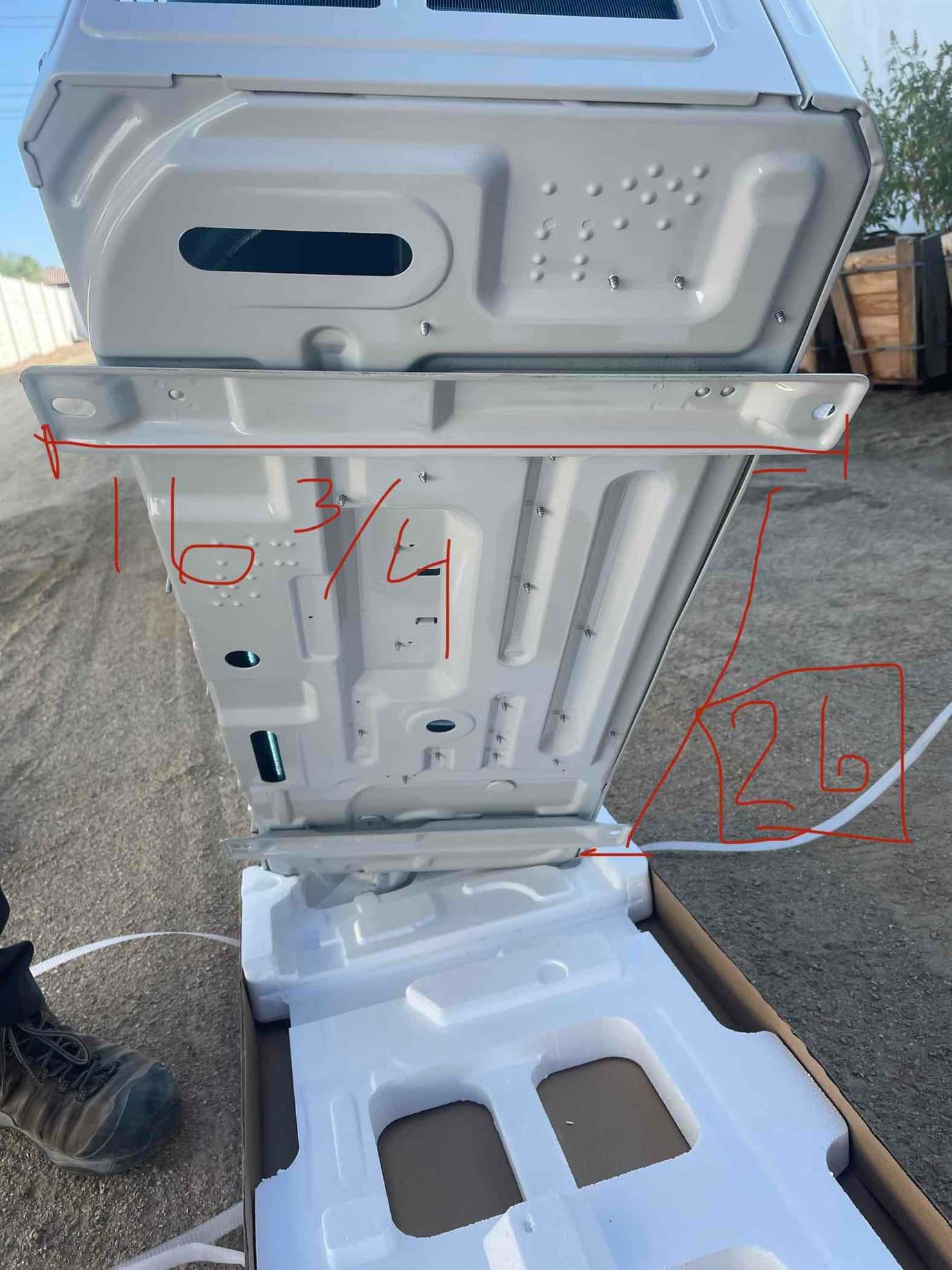 Indoor mini-split air handler casing unboxed with mounting brackets visible and handwritten measurements marked for placement during installation.