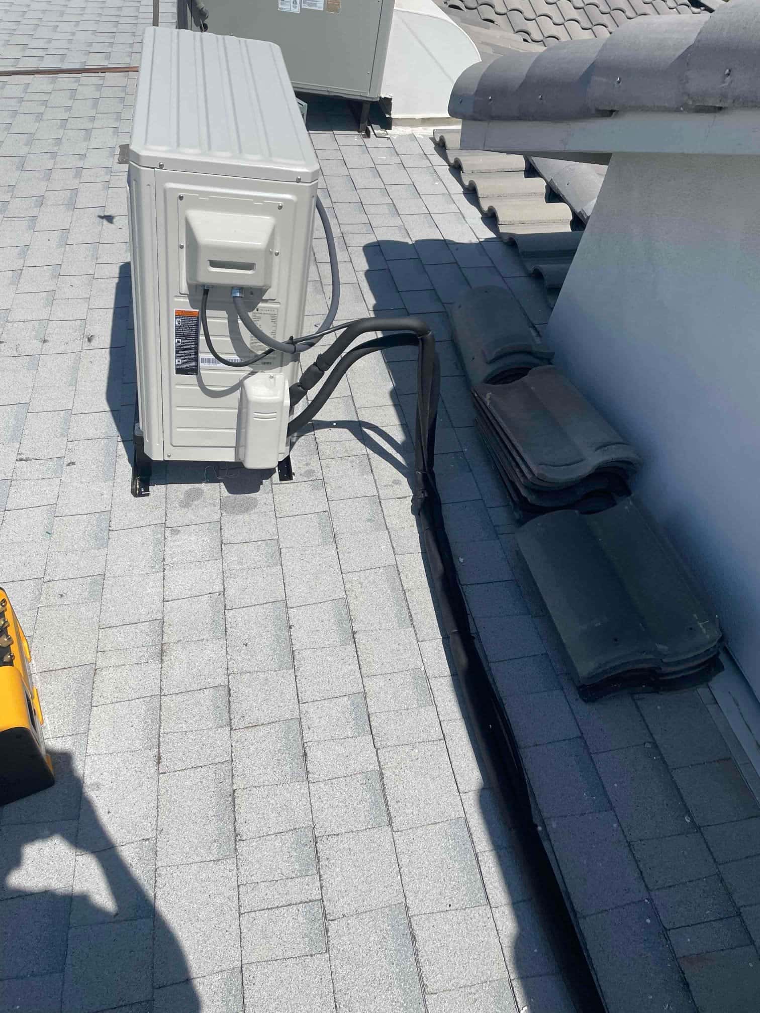 Mini-split outdoor unit mounted on rooftop with insulated line set and control wiring routed neatly along the shingles.