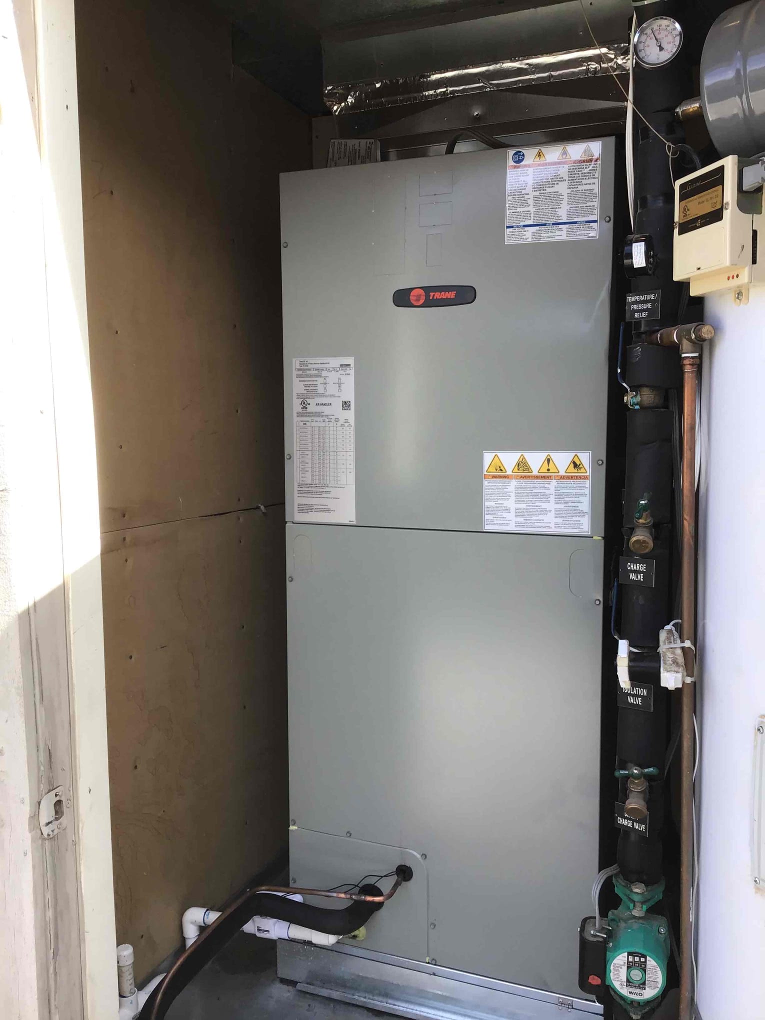 New indoor air handler installed in a dedicated closet with connected condensate drain and insulated refrigerant lines.